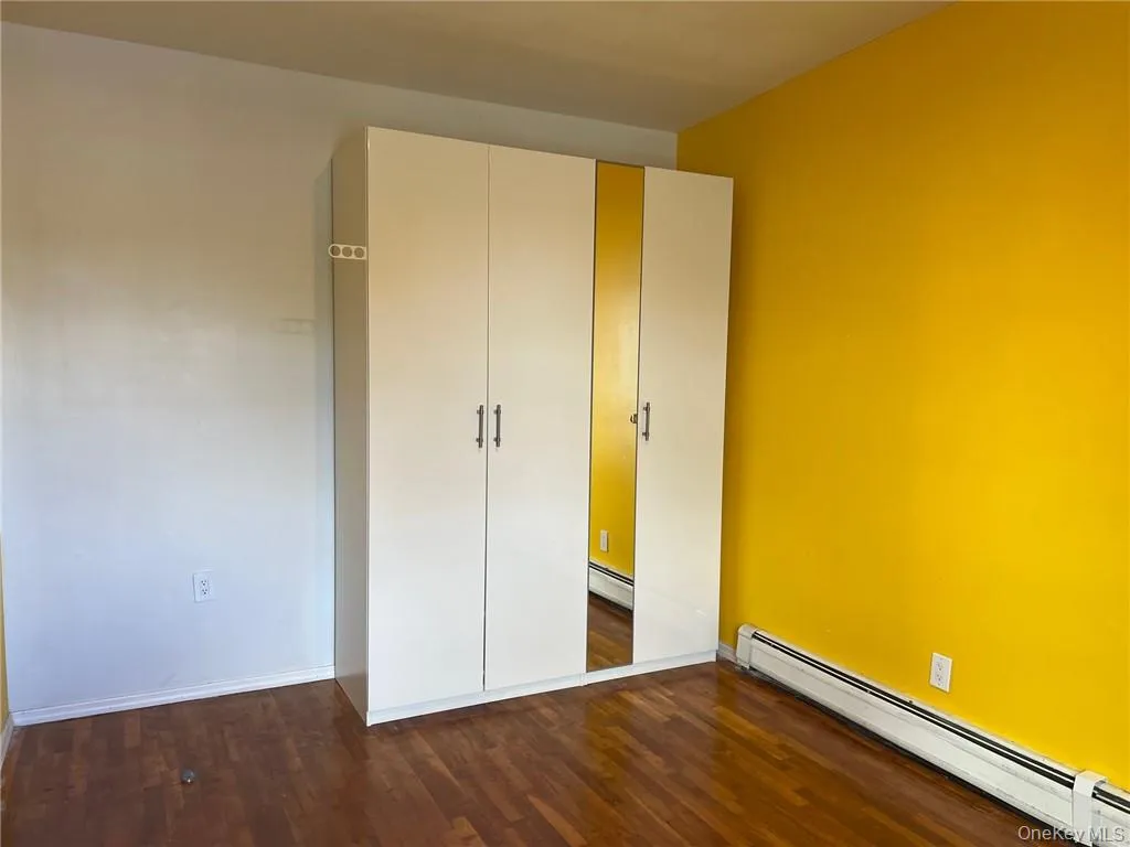 Unfurnished bedroom featuring a closet, dark hardwood / wood-style flooring, and a baseboard radiator Unfurnished bedroom featuring a closet, dark hardwood / wood-style flooring, and a baseboard radiator