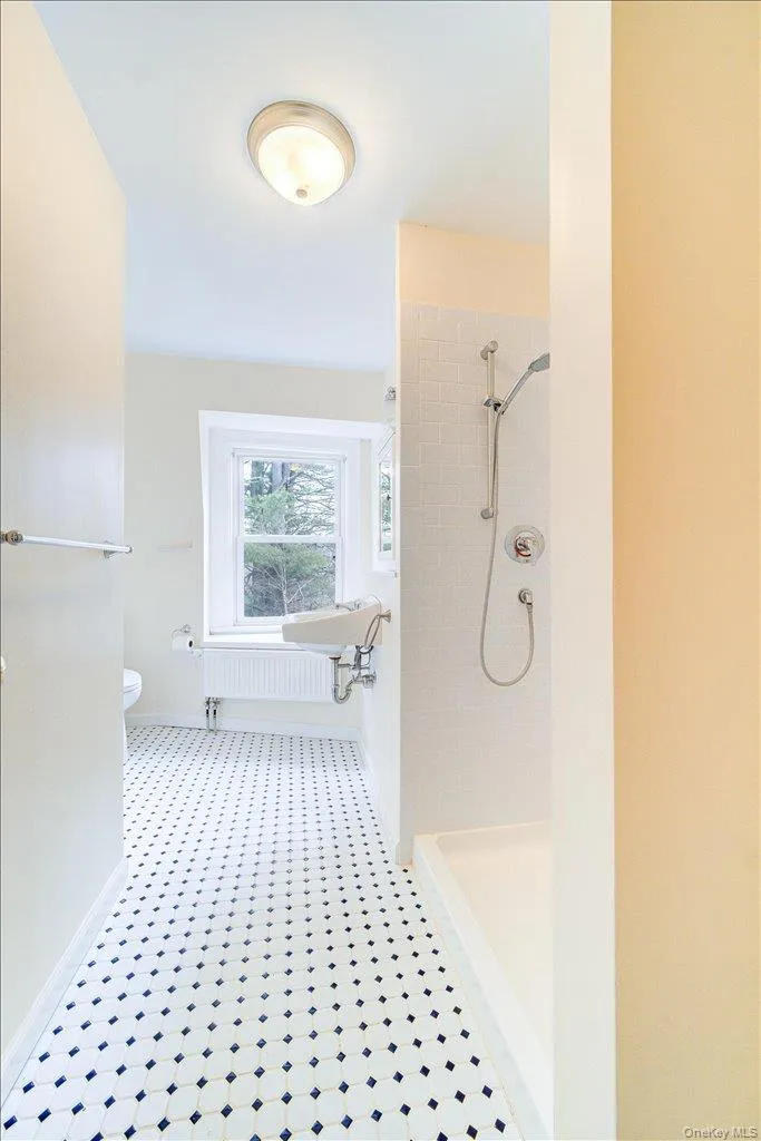 Bathroom with radiator heating unit, toilet, and tiled shower Bathroom with radiator heating unit, toilet, and tiled shower