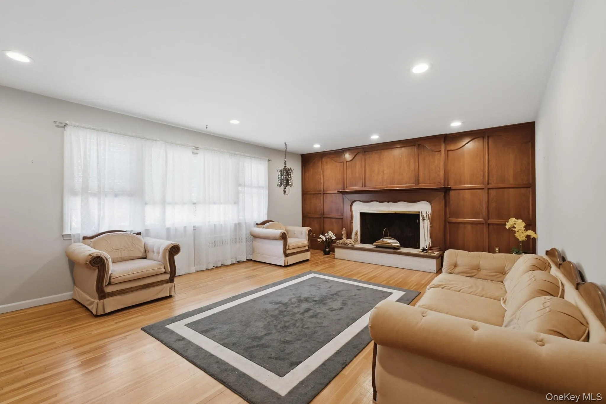 Spacious living room highlighted by beautiful wood-accented fireplace, hardwood floors, and recessed lighting. Spacious living room highlighted by beautiful wood-accented fireplace, hardwood floors, and recessed lighting.
