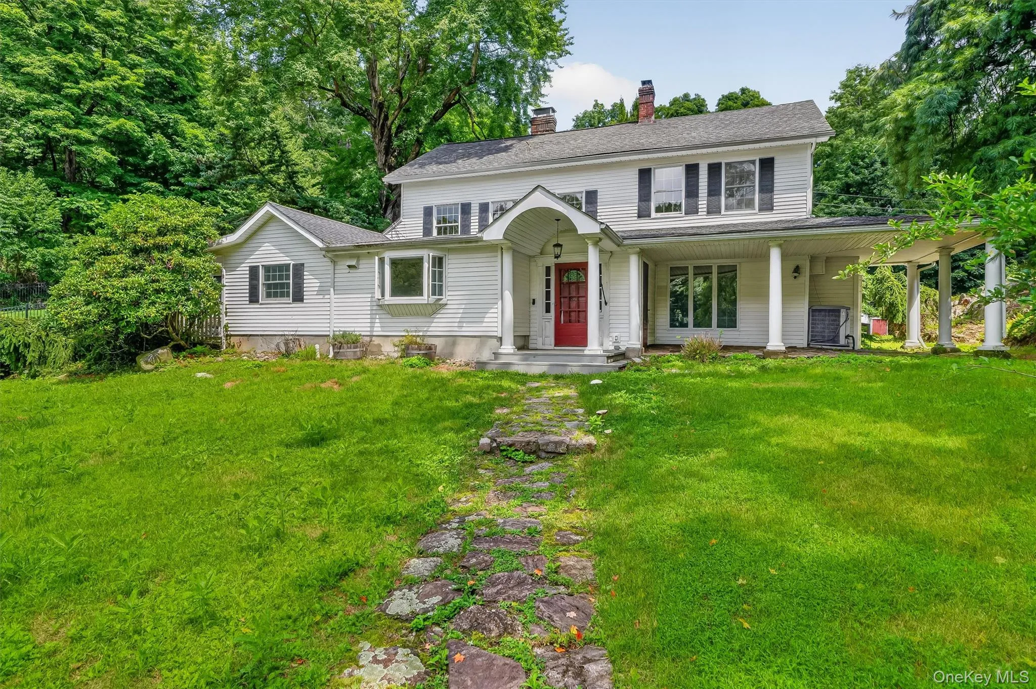 White siding exterior with a red entry door, covered front porch, columned side porch, and a bay window White siding exterior with a red entry door, covered front porch, columned side porch, and a bay window