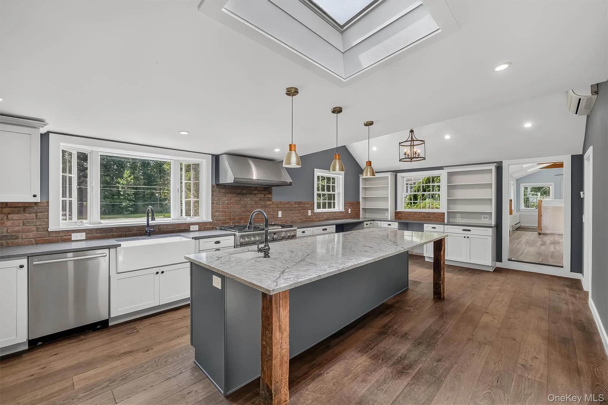 Kitchen featuring a center island with a stone countertop, wood-finish flooring, a farmhouse sink, chef grade stainless steel appliances, and a skylight Kitchen featuring a center island with a stone countertop, wood-finish flooring, a farmhouse sink, chef grade stainless steel appliances, and a skylight