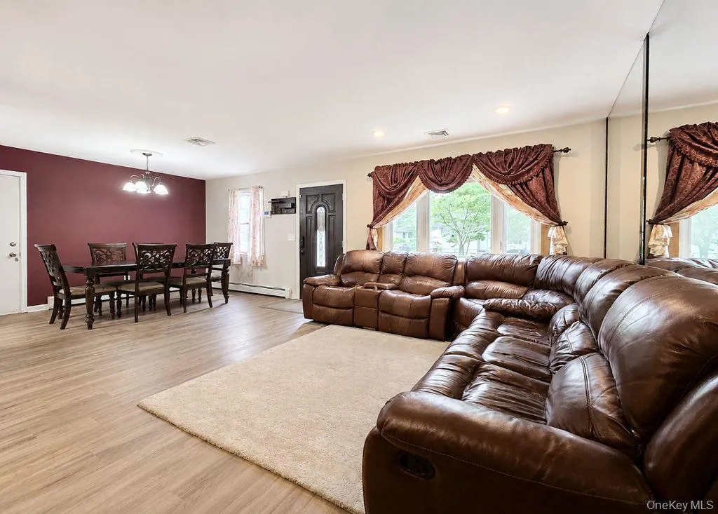 Open-concept living area featuring wood-finish flooring, recessed lighting, and a prominent dining space with a chandelier Open-concept living area featuring wood-finish flooring, recessed lighting, and a prominent dining space with a chandelier