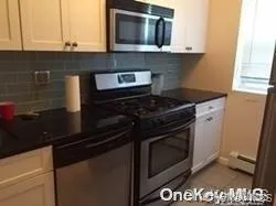 Kitchen with stainless steel appliances, decorative backsplash, and dark countertops Kitchen with stainless steel appliances, decorative backsplash, and dark countertops