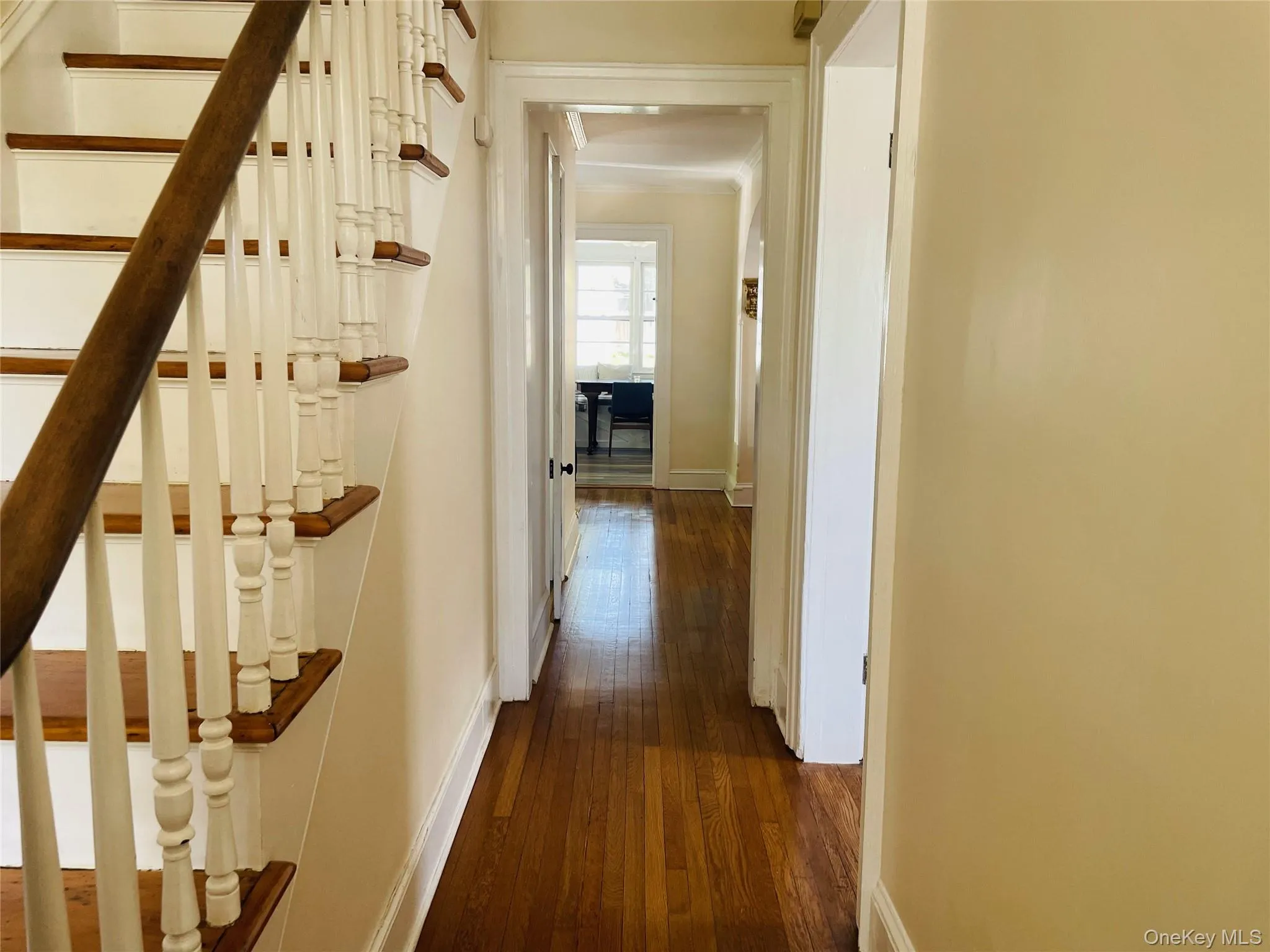 Hall featuring baseboards, wood finished floors, and stairs Hall featuring baseboards, wood finished floors, and stairs