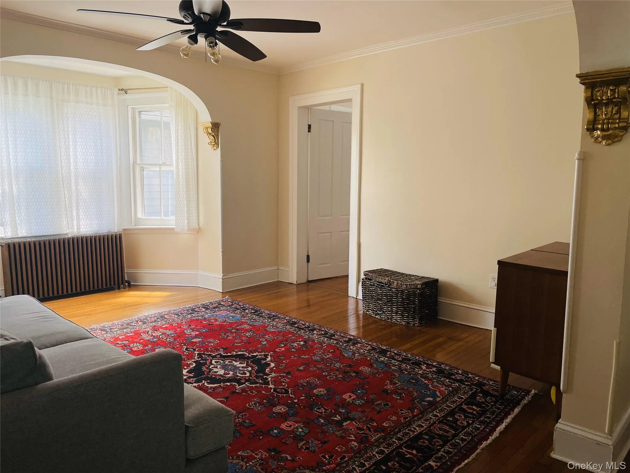 Living area featuring ceiling fan, arched walkways, wood finished floors, baseboards Living area featuring ceiling fan, arched walkways, wood finished floors, baseboards