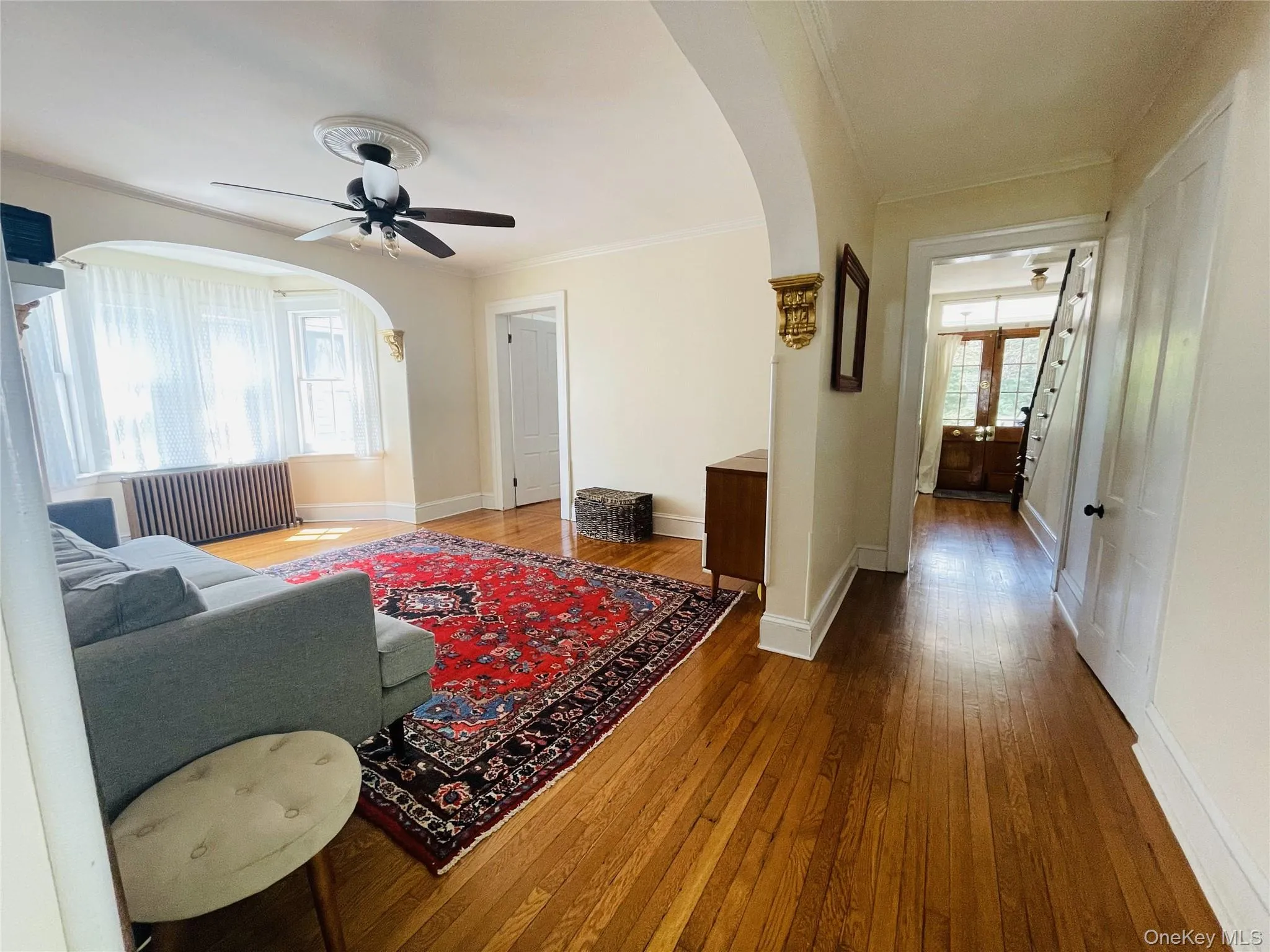 Living room with arched walkways, ceiling fan, and hardwood floors Living room with arched walkways, ceiling fan, and hardwood floors