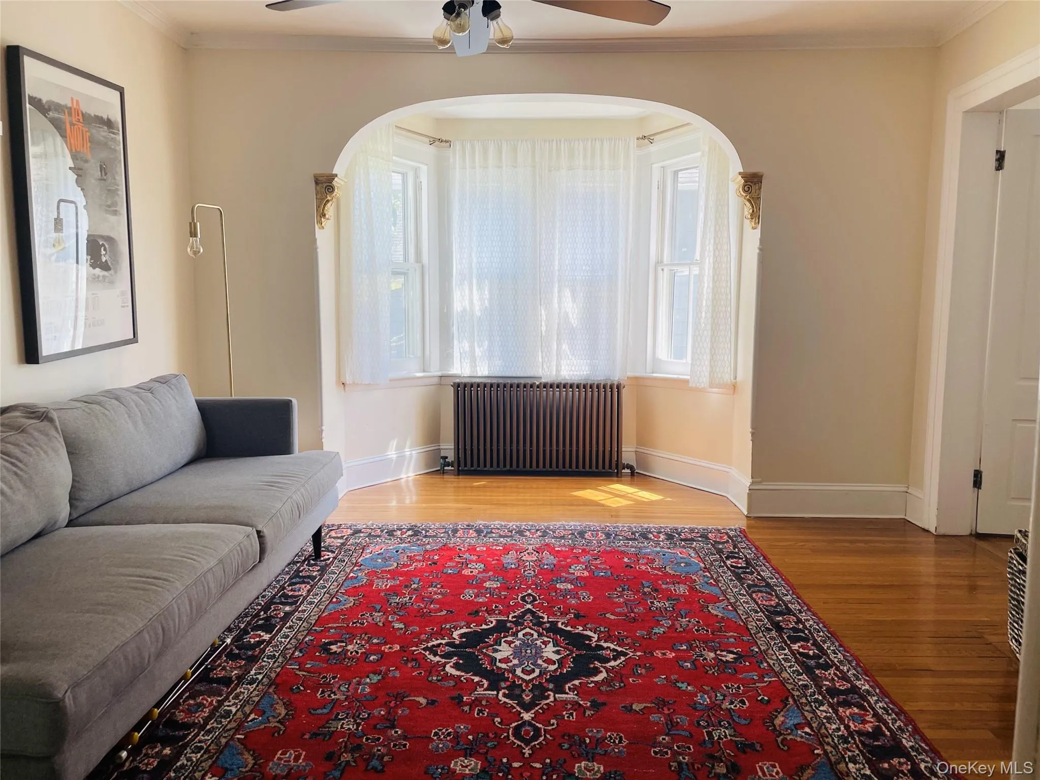 Living area featuring ornamental molding, wood floors, ceiling fan and arched walkways Living area featuring ornamental molding, wood floors, ceiling fan and arched walkways