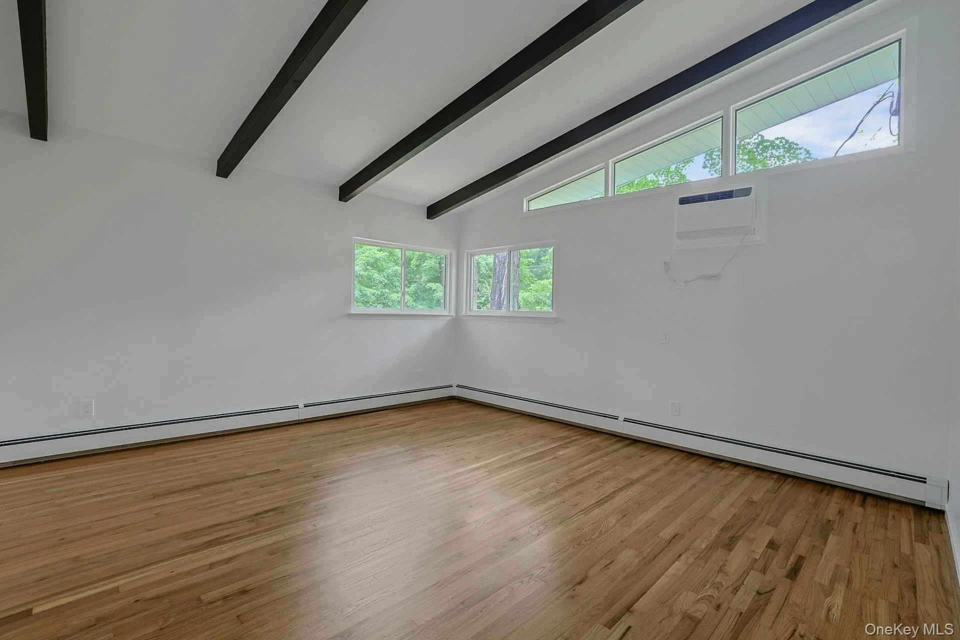 Spacious Primary bedroom with hardwood floor and beamed ceiling Spacious Primary bedroom with hardwood floor and beamed ceiling