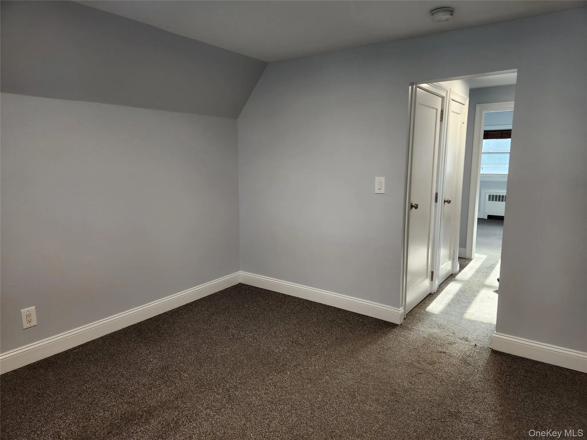 Baseboards, carpet flooring, radiator, and vauted ceiling Baseboards, carpet flooring, radiator, and vauted ceiling