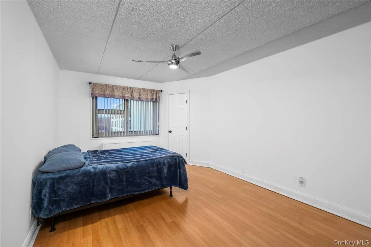 Room featuring wood-finish flooring, a contemporary ceiling fan, and white baseboards Room featuring wood-finish flooring, a contemporary ceiling fan, and white baseboards