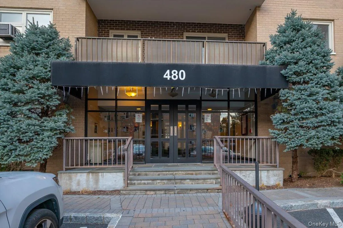 Brick exterior with a prominent entrance featuring a dark awning and address numbers Brick exterior with a prominent entrance featuring a dark awning and address numbers