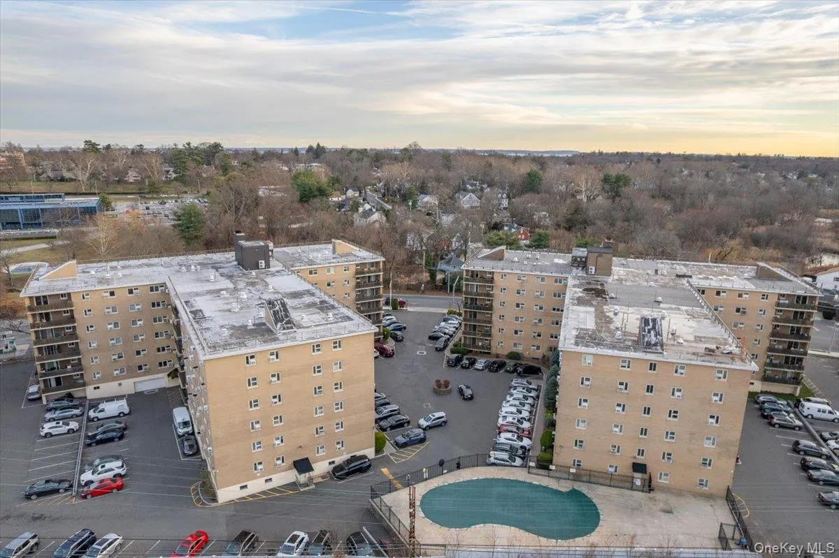 Multi-building apartment complex featuring a covered swimming pool, extensive surface parking, and individual balconies on several units Multi-building apartment complex featuring a covered swimming pool, extensive surface parking, and individual balconies on several units