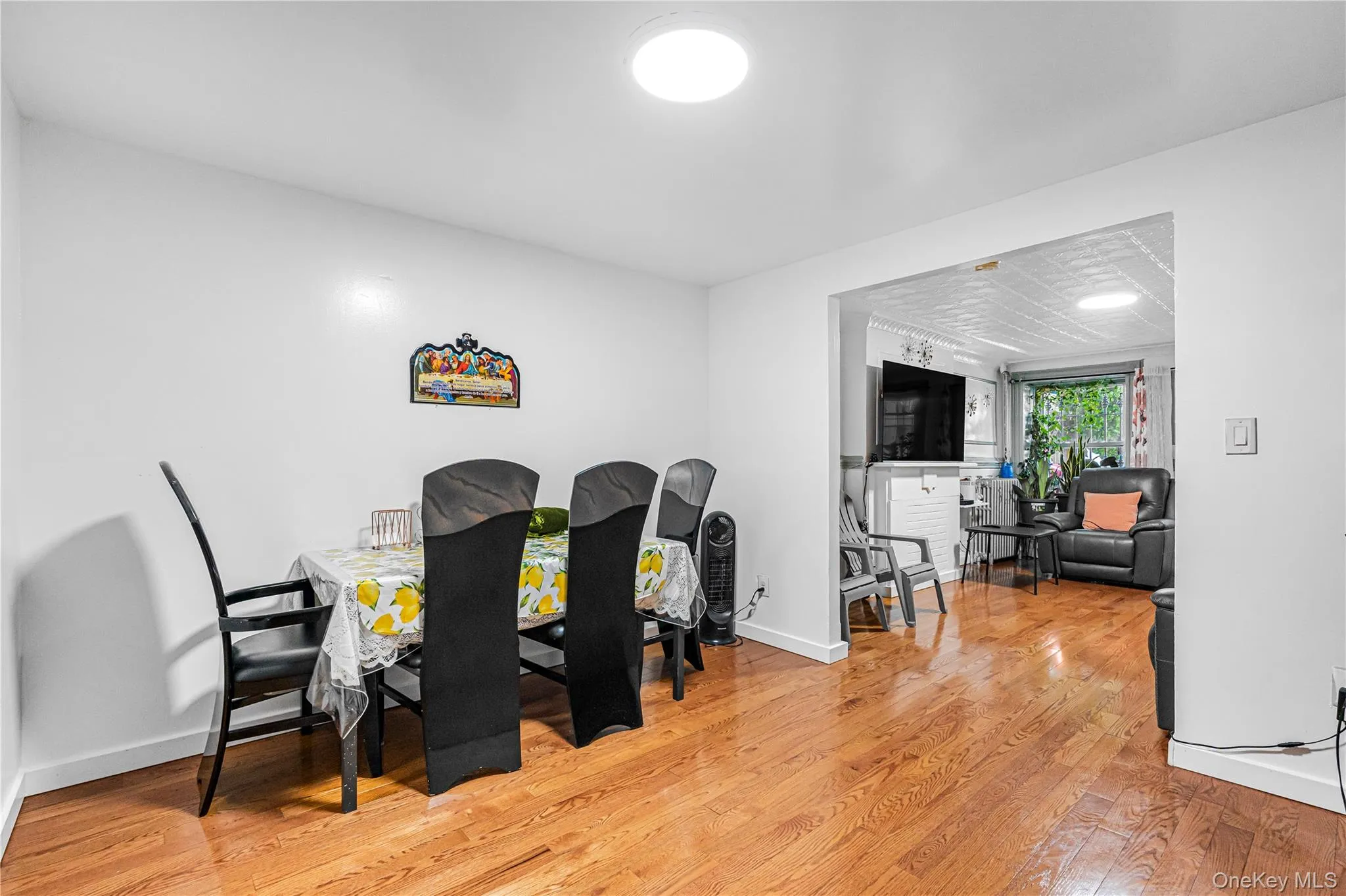 Dining area featuring wood-finish flooring, white walls, and an open entryway to an additional living space Dining area featuring wood-finish flooring, white walls, and an open entryway to an additional living space