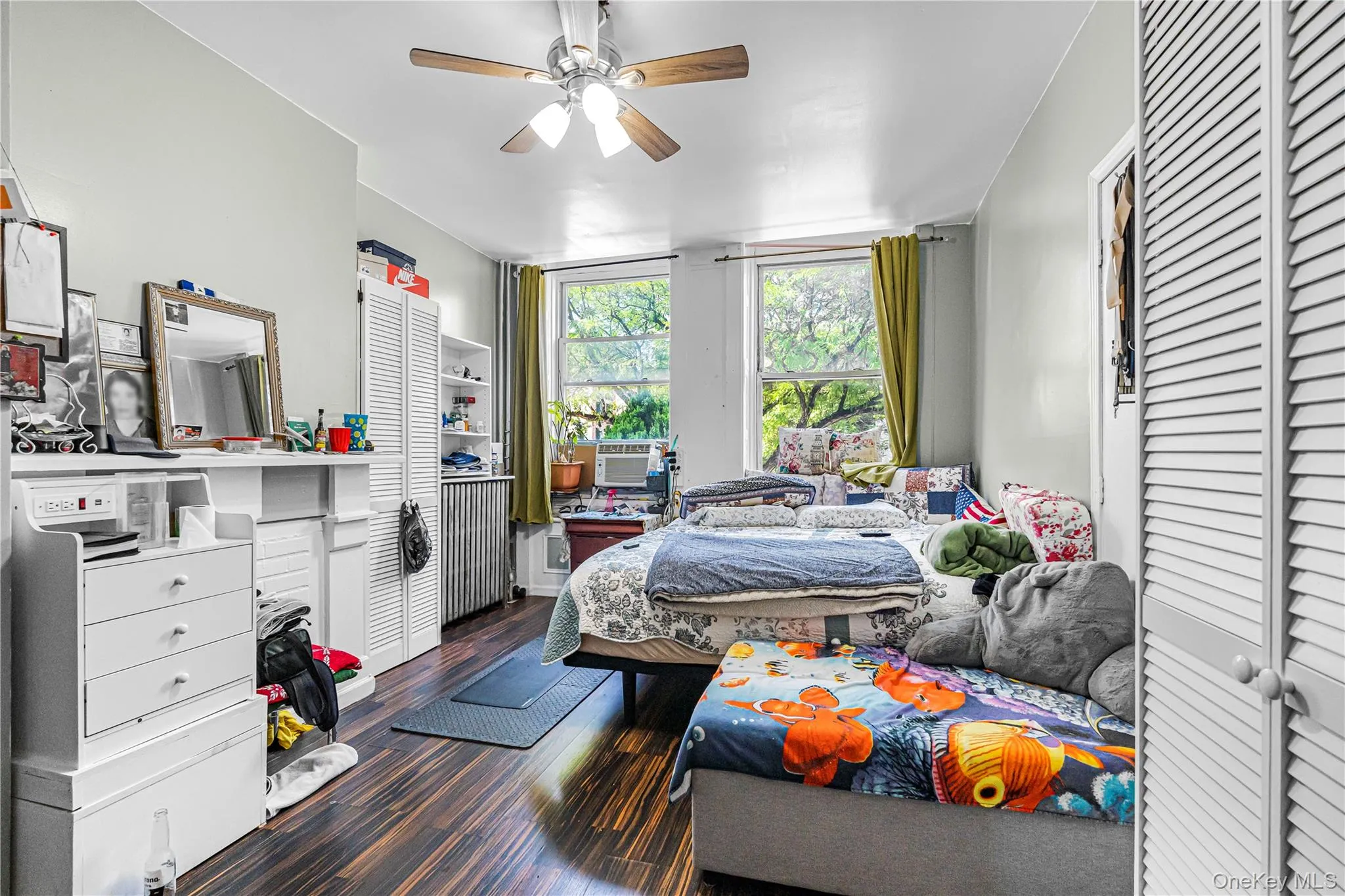 Bright interior space featuring wood-finish flooring, a ceiling fan with light fixture, and two large windows Bright interior space featuring wood-finish flooring, a ceiling fan with light fixture, and two large windows