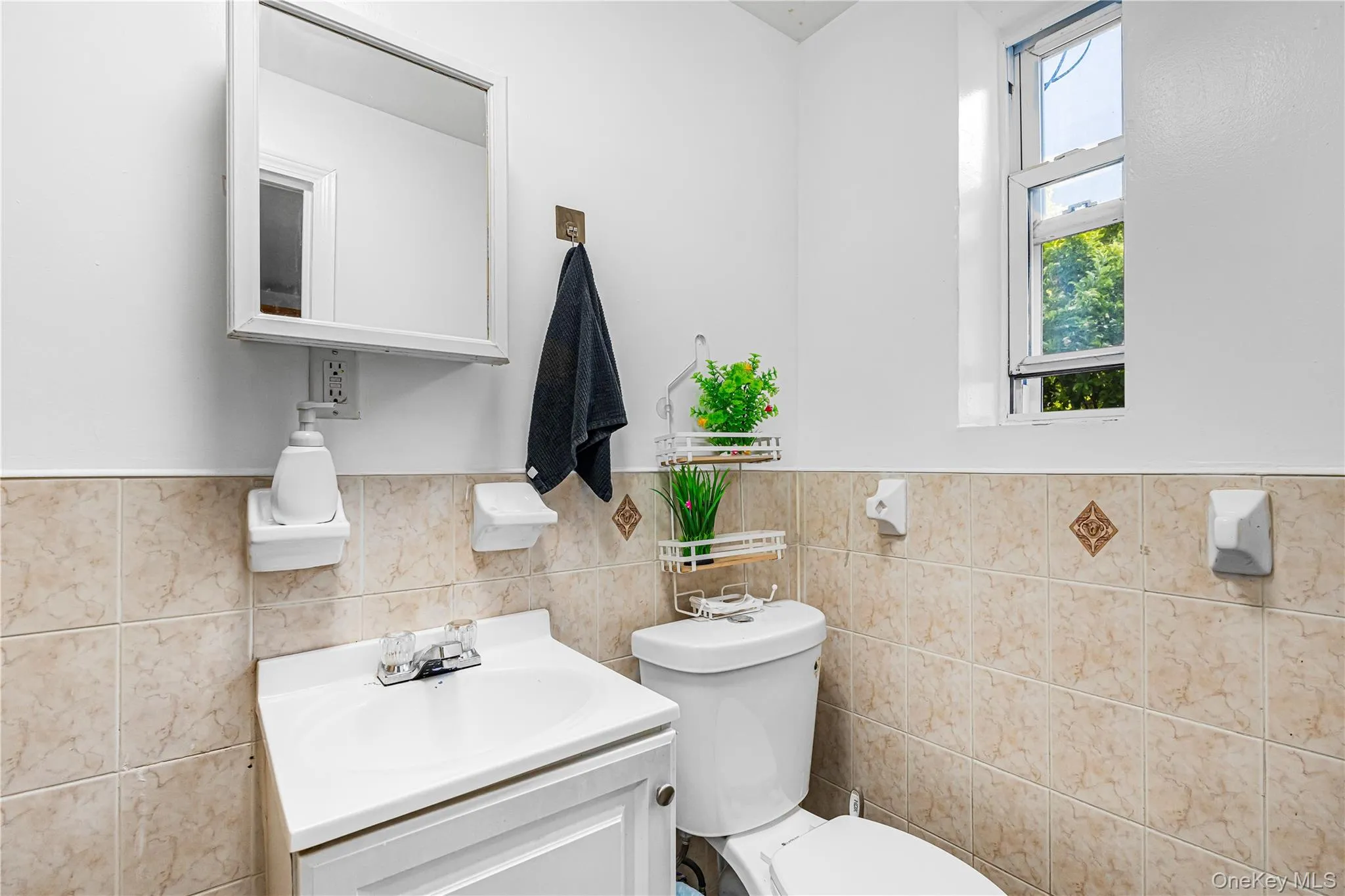Bathroom featuring a single vanity, tiled walls, and an overhead medicine cabinet Bathroom featuring a single vanity, tiled walls, and an overhead medicine cabinet