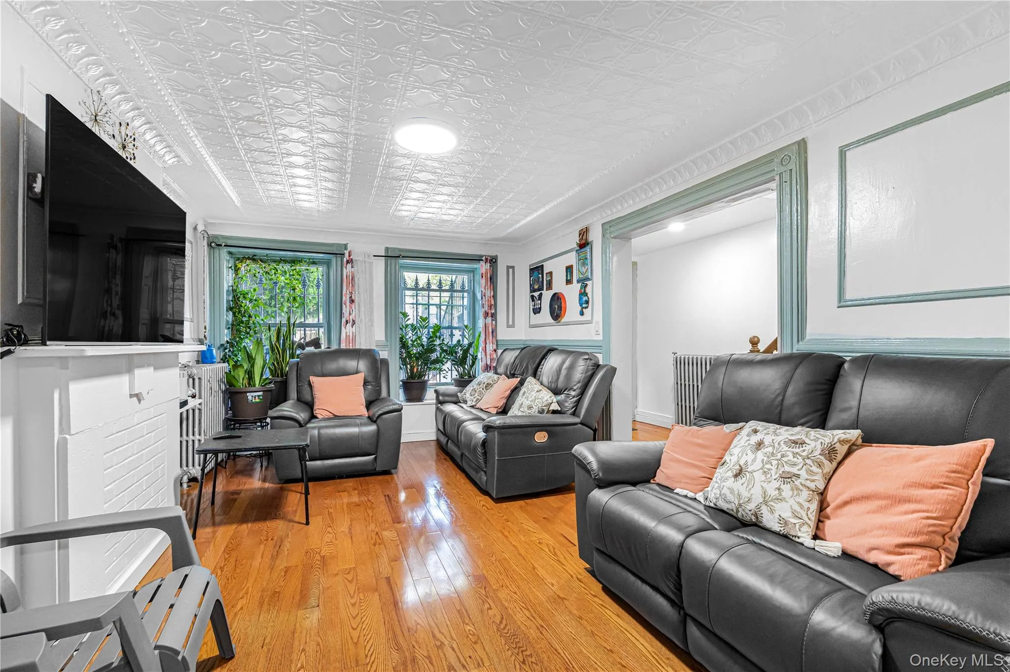 Living area featuring wood-finish flooring, an ornate white ceiling, and decorative window moldings Living area featuring wood-finish flooring, an ornate white ceiling, and decorative window moldings