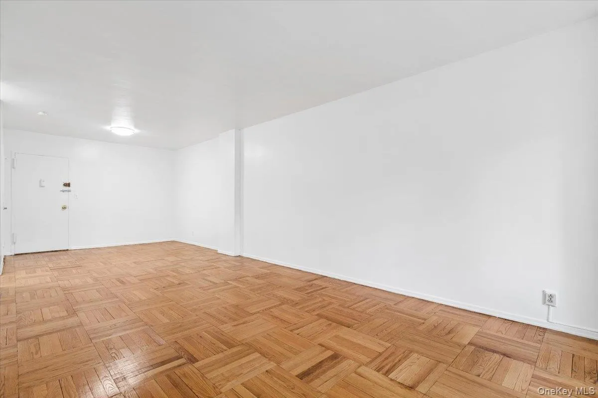Spacious room featuring parquet wood flooring and clean white walls Spacious room featuring parquet wood flooring and clean white walls
