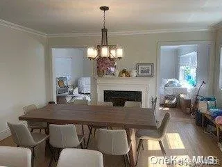 Dining room with a fireplace, a chandelier, crown molding, and wood finished floors Dining room with a fireplace, a chandelier, crown molding, and wood finished floors