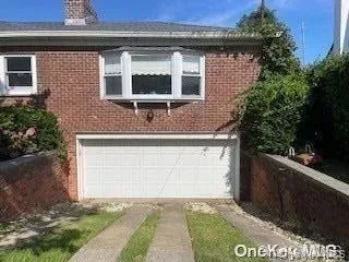 View of side of property featuring brick siding, a garage, a chimney, and driveway View of side of property featuring brick siding, a garage, a chimney, and driveway