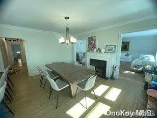 Dining room with crown molding, wood finished floors, a chandelier, and a fireplace with flush hearth Dining room with crown molding, wood finished floors, a chandelier, and a fireplace with flush hearth