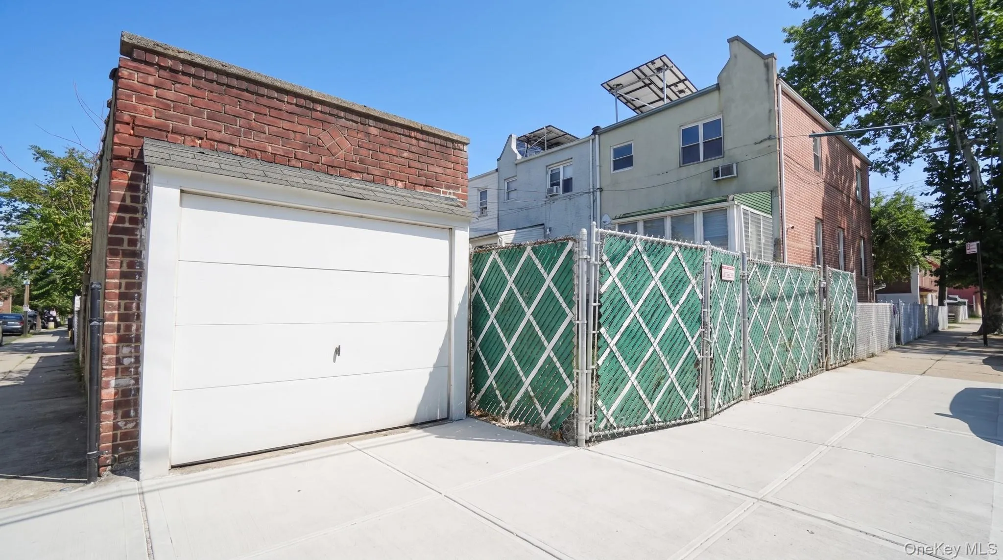 Detached brick garage with a white overhead door and shingle roof Detached brick garage with a white overhead door and shingle roof