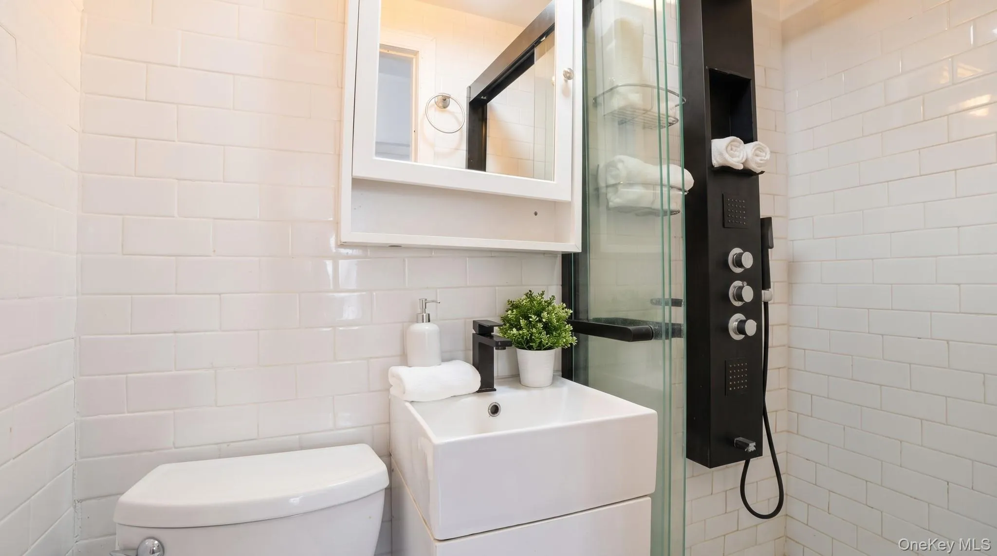 Compact bathroom featuring white subway tile walls Compact bathroom featuring white subway tile walls
