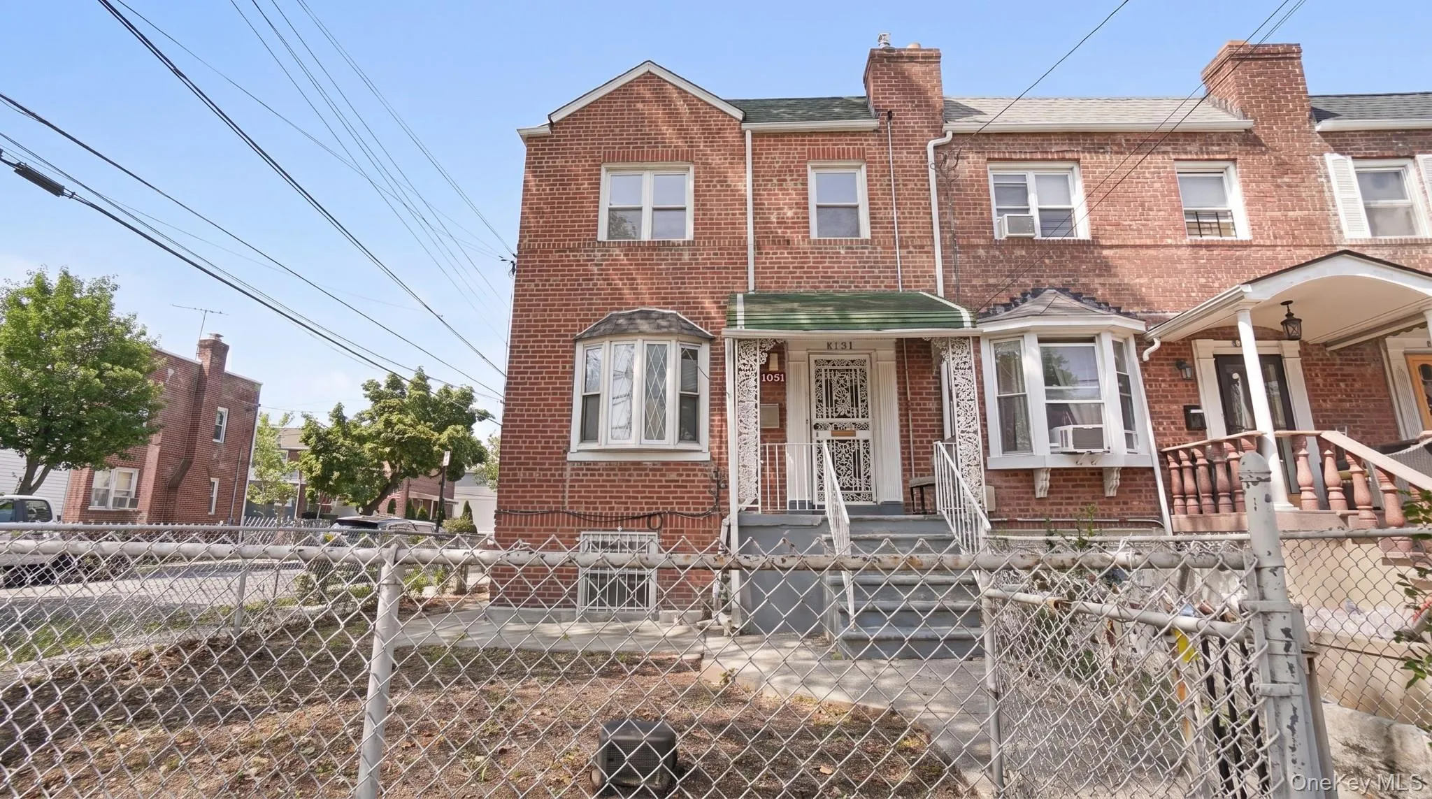 Brick exterior townhouse featuring a bay window, concrete steps, and a decorative metal porch awning Brick exterior townhouse featuring a bay window, concrete steps, and a decorative metal porch awning