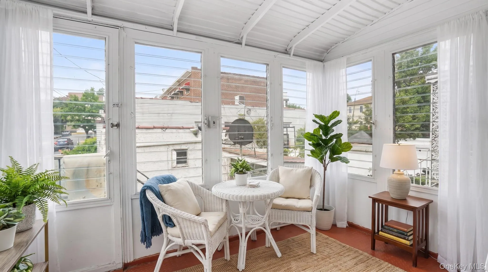 Sunroom featuring multiple vertical windows with horizontal louvers, a slatted ceiling, and an orange-hued floor Sunroom featuring multiple vertical windows with horizontal louvers, a slatted ceiling, and an orange-hued floor
