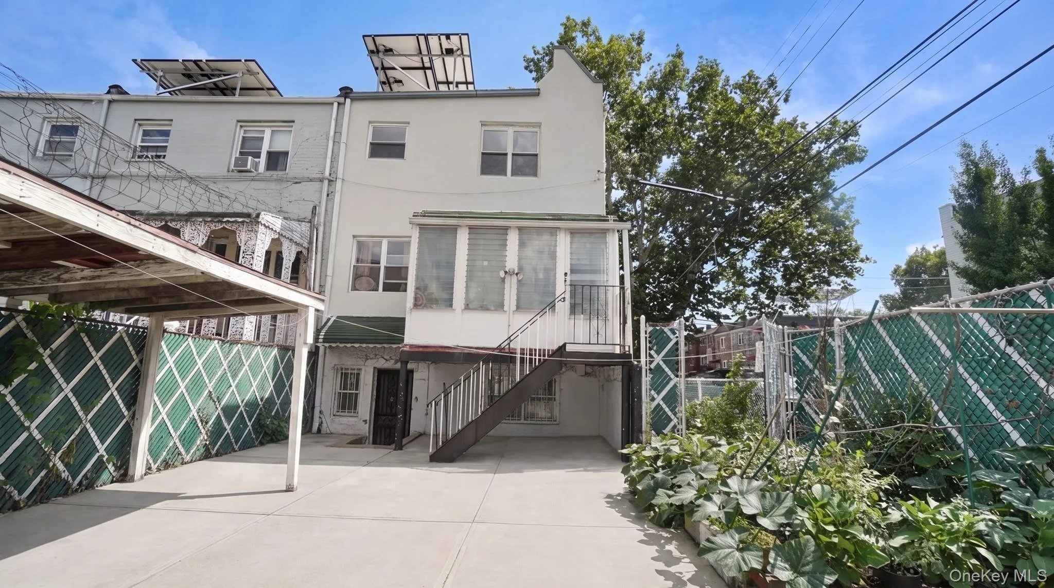 Rear exterior featuring a ground-level covered parking area and an upper-level enclosed patio Rear exterior featuring a ground-level covered parking area and an upper-level enclosed patio