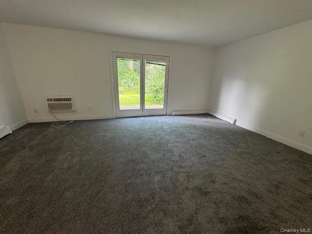 Living room area with wall unit air condition and newer carpet flooring. Living room area with wall unit air condition and newer carpet flooring.