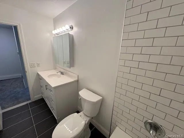 Bathroom with vanity, toilet, tiled flooring and walls Bathroom with vanity, toilet, tiled flooring and walls