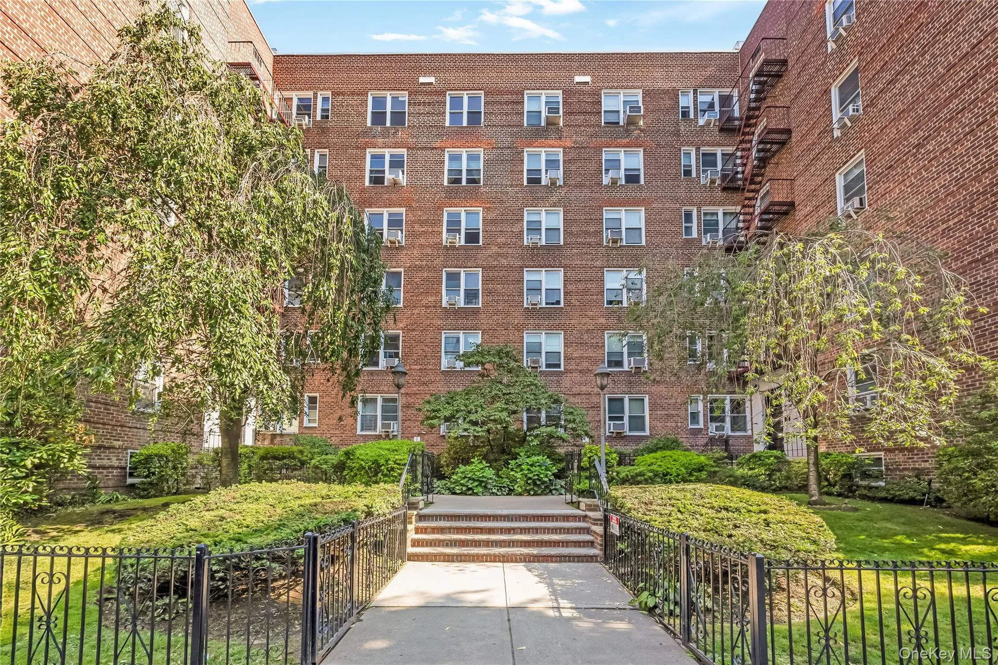 Brick exterior building featuring multiple windows and a black wrought iron fence Brick exterior building featuring multiple windows and a black wrought iron fence