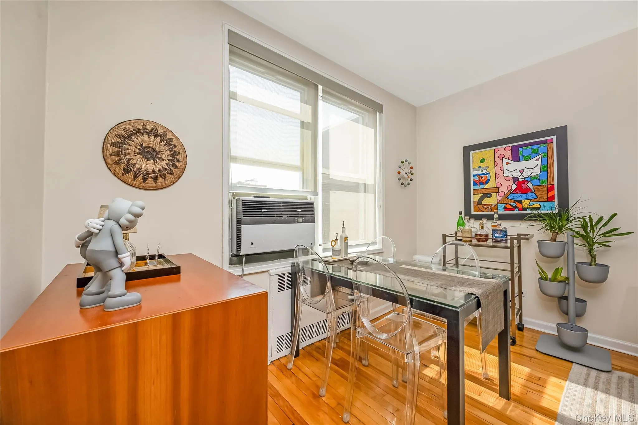 Dining area featuring wood-finish flooring, an in-window air conditioning unit, and a window with blinds Dining area featuring wood-finish flooring, an in-window air conditioning unit, and a window with blinds