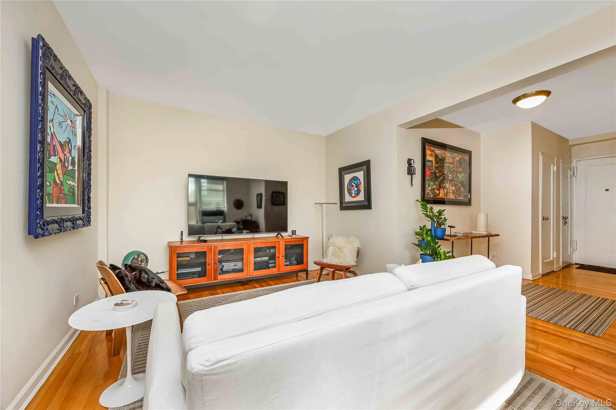 Living area featuring hardwood flooring, light-toned wall paint, and a built-in ceiling light fixture Living area featuring hardwood flooring, light-toned wall paint, and a built-in ceiling light fixture