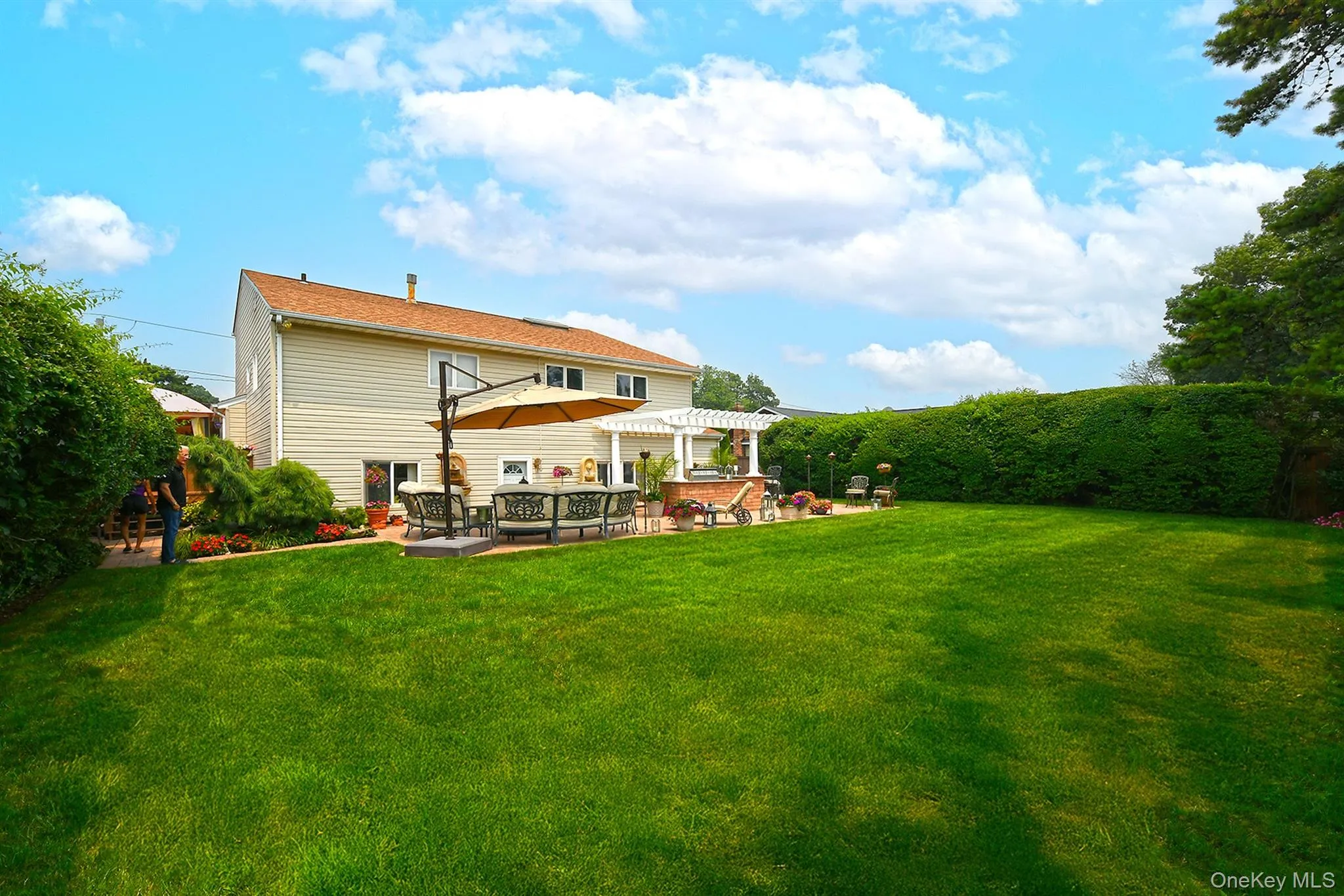 Spacious backyard featuring a substantial lawn area, a paver patio, and a white pergola Spacious backyard featuring a substantial lawn area, a paver patio, and a white pergola