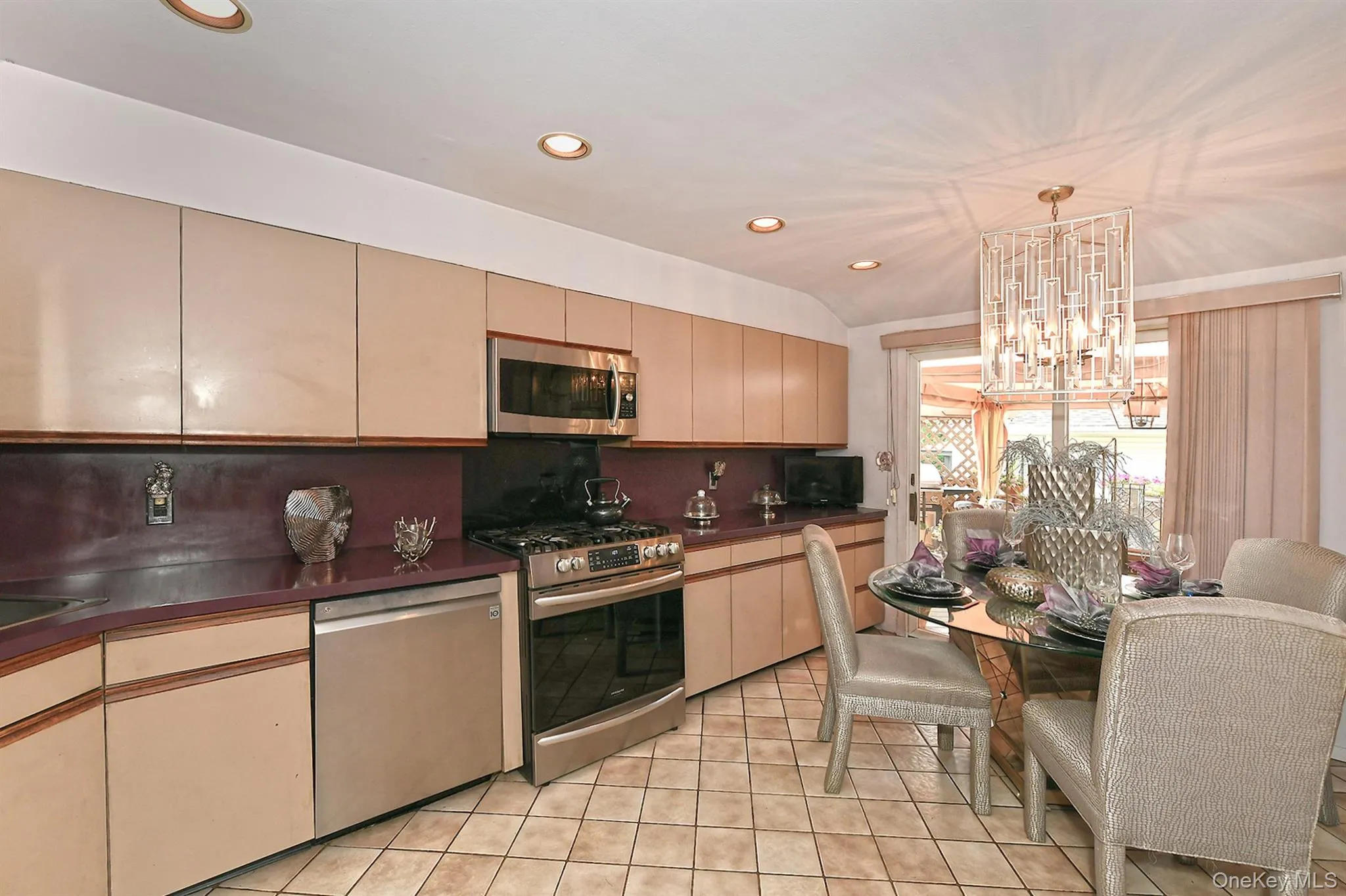 Kitchen area featuring light cabinetry, purple countertops and backsplash, stainless steel appliances, and tile flooring Kitchen area featuring light cabinetry, purple countertops and backsplash, stainless steel appliances, and tile flooring