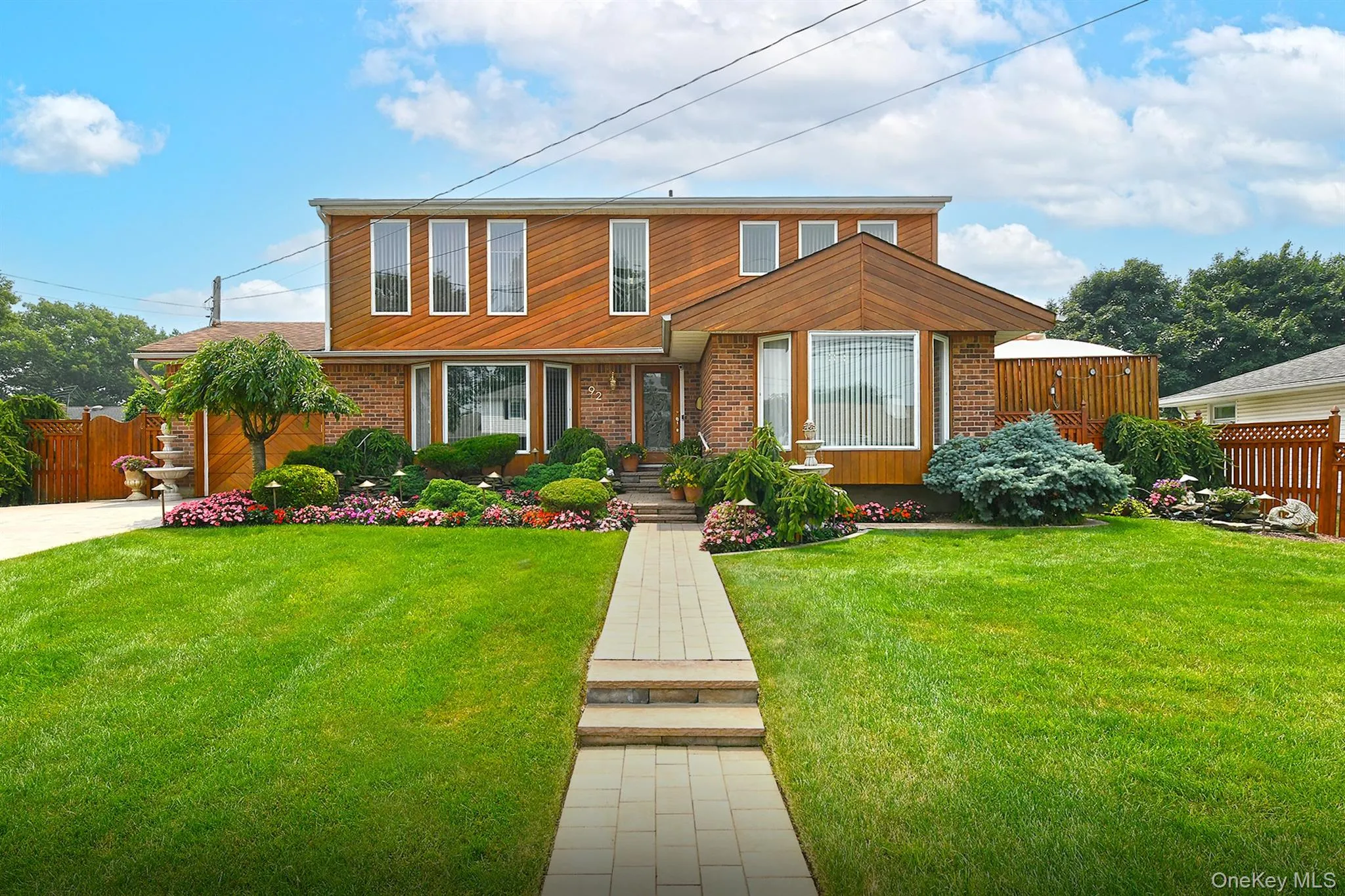 Two-story residence featuring brick and vertical wood-finish siding with multiple windows Two-story residence featuring brick and vertical wood-finish siding with multiple windows