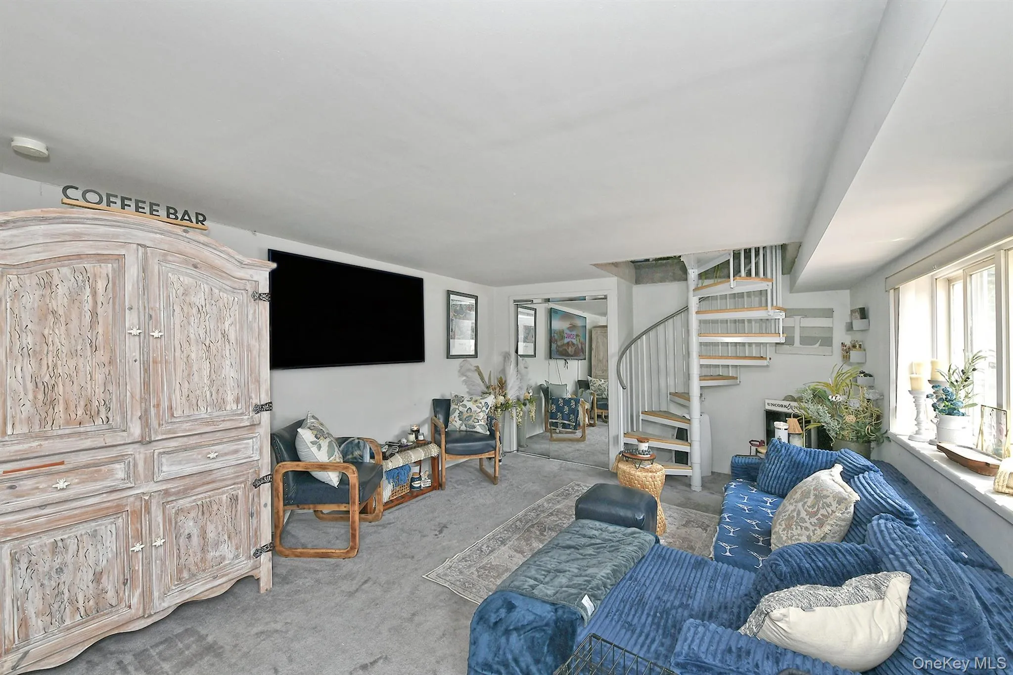 Carpeted room featuring a white spiral staircase, recessed lighting, and a large window Carpeted room featuring a white spiral staircase, recessed lighting, and a large window