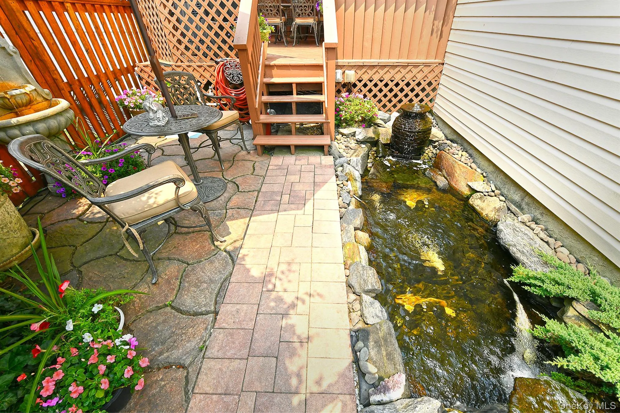 Outdoor patio area featuring a stone water feature, natural rock accents, and a wood privacy fence Outdoor patio area featuring a stone water feature, natural rock accents, and a wood privacy fence