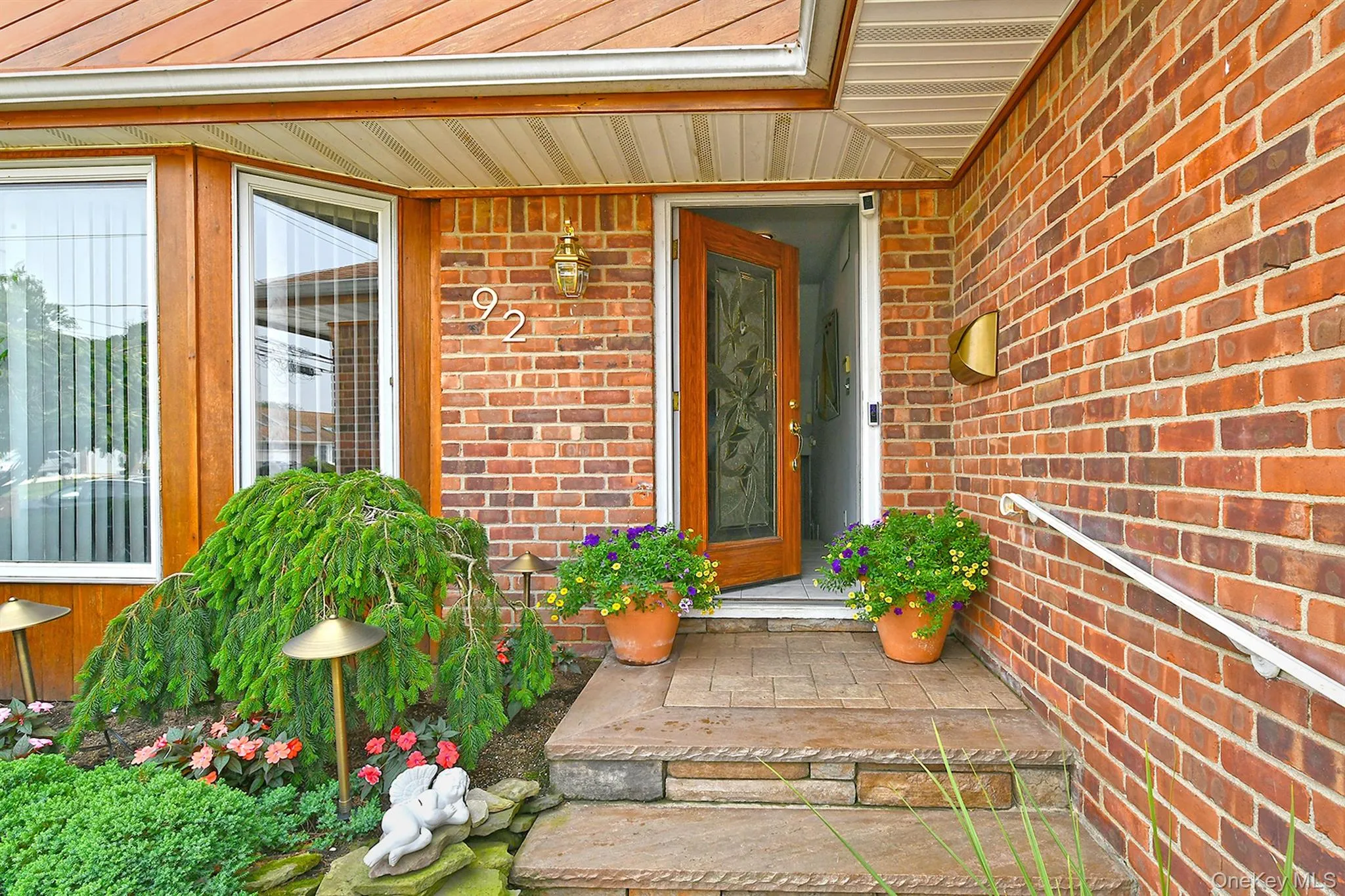 Brick exterior with wood-frame bay windows, a decorative entry door, and a stone-tiled entryway Brick exterior with wood-frame bay windows, a decorative entry door, and a stone-tiled entryway