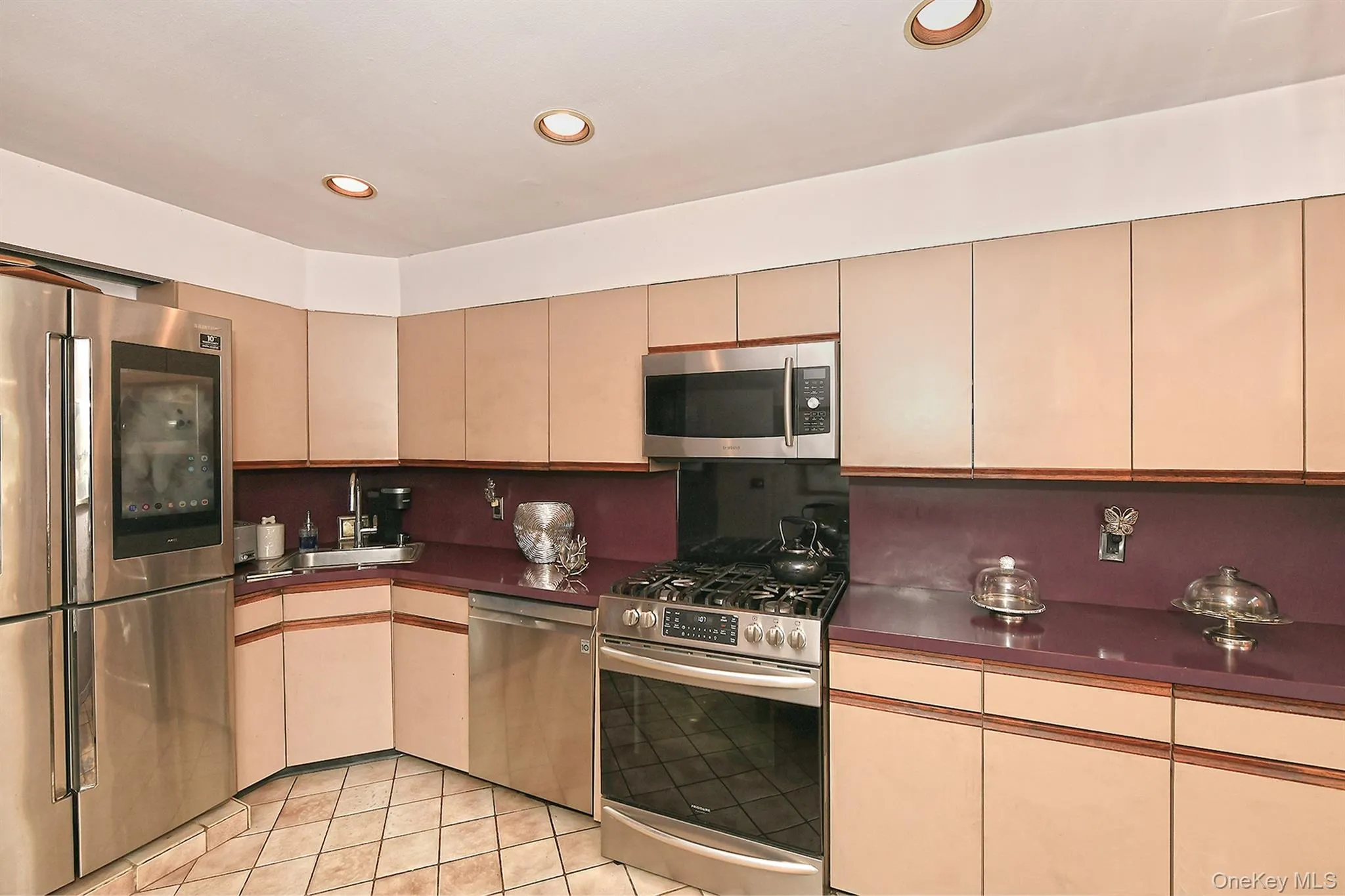 Kitchen featuring stainless steel appliances, recessed lighting, tile flooring, contemporary cabinetry, and purple countertops Kitchen featuring stainless steel appliances, recessed lighting, tile flooring, contemporary cabinetry, and purple countertops