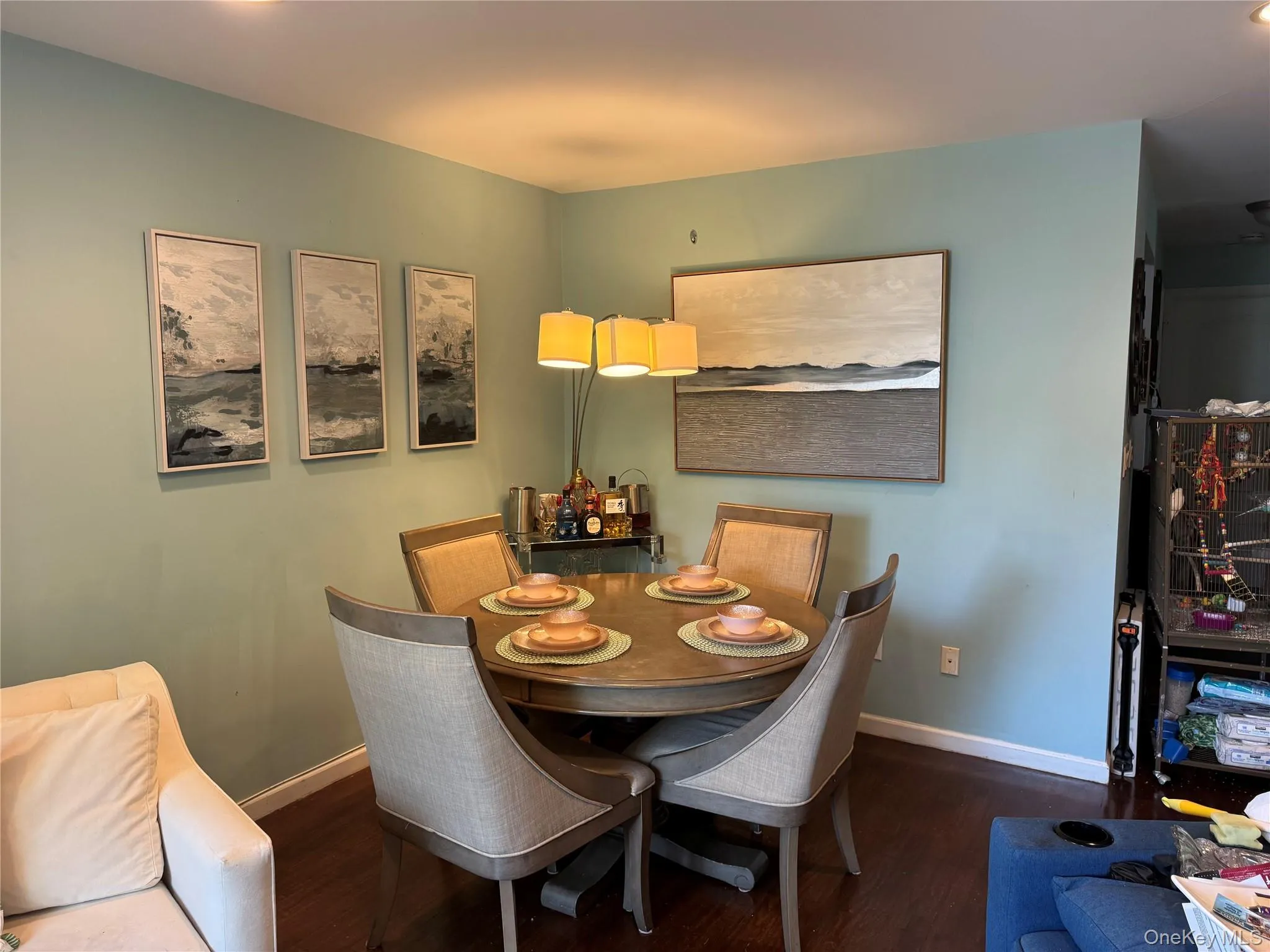 Dining area with hardwood-finish flooring, light blue wall paint, and white baseboards Dining area with hardwood-finish flooring, light blue wall paint, and white baseboards
