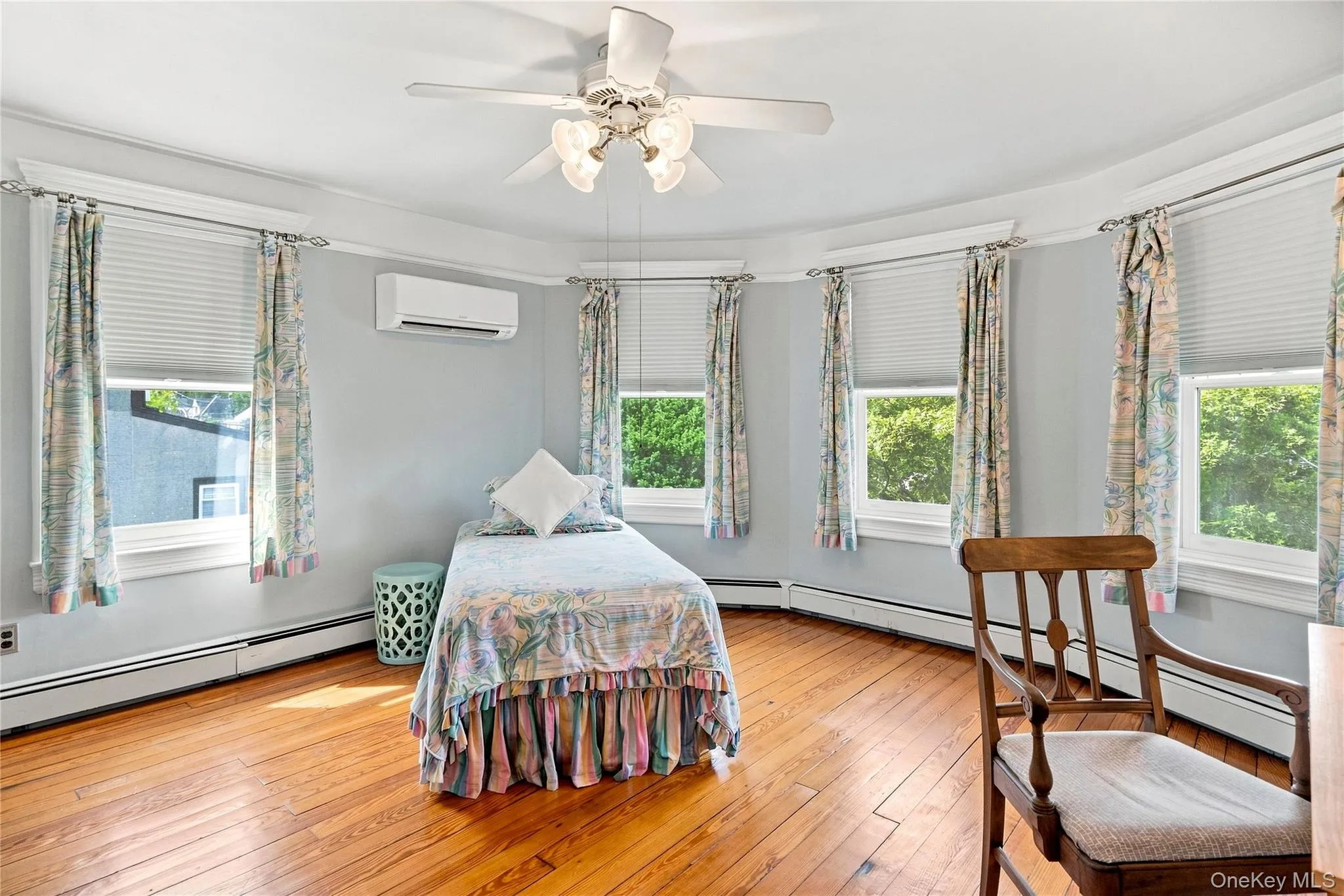 Hardwood flooring, multiple windows with blinds, ceiling fan, wall-mounted mini-split unit, and baseboard heating Hardwood flooring, multiple windows with blinds, ceiling fan, wall-mounted mini-split unit, and baseboard heating