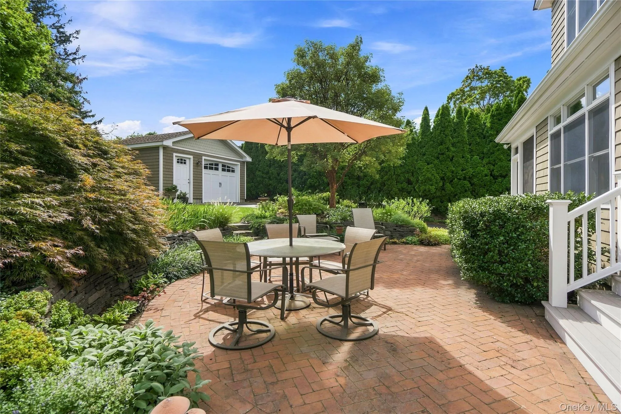 Brick paver patio with a detached garage and landscaped garden beds Brick paver patio with a detached garage and landscaped garden beds