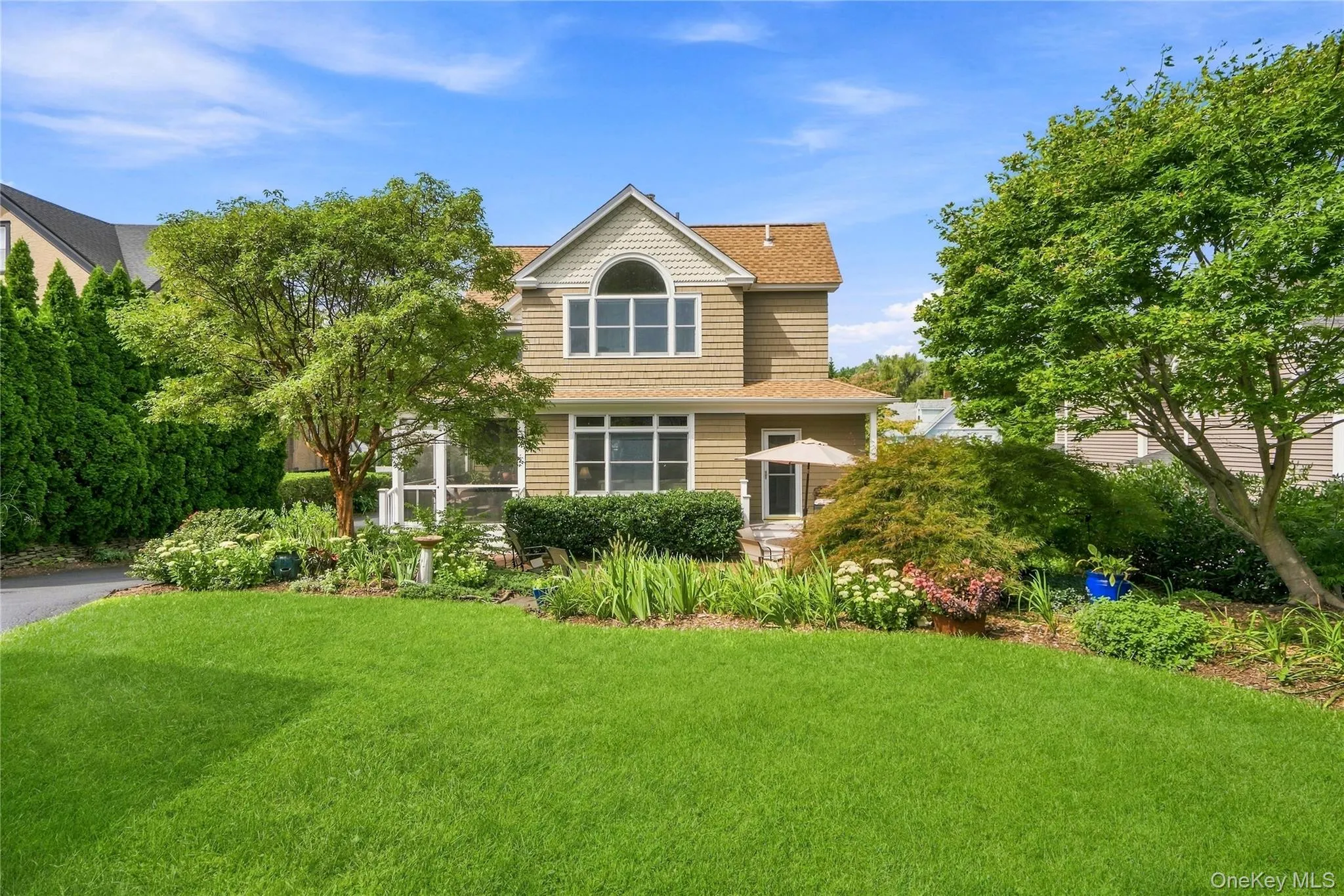 Back of House with siding exterior, arched window, and gabled roof and Manicured lawn Back of House with siding exterior, arched window, and gabled roof and Manicured lawn