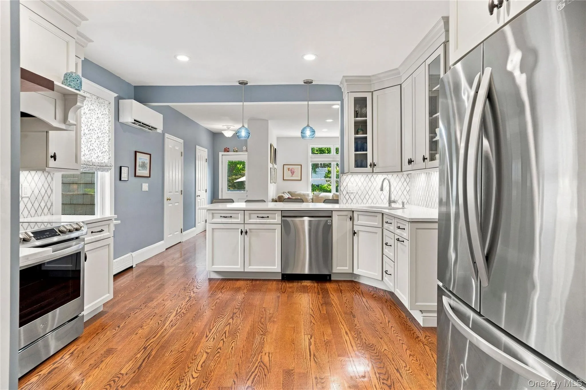 Hardwood flooring, stainless steel appliances, white cabinetry, recessed lighting, and Marble backsplash Hardwood flooring, stainless steel appliances, white cabinetry, recessed lighting, and Marble backsplash