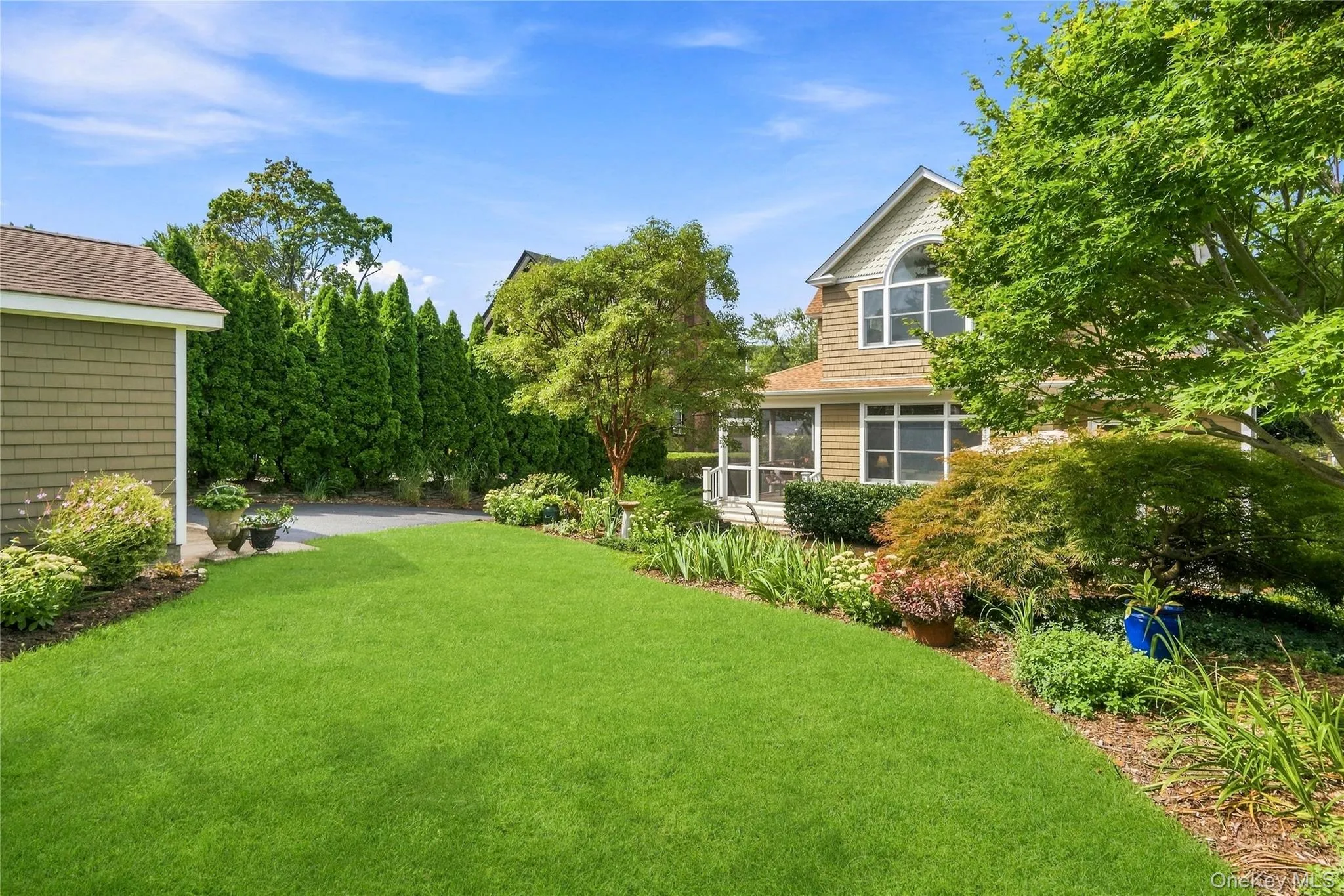Expansive green lawn with mature landscaping and a well-maintained driveway Expansive green lawn with mature landscaping and a well-maintained driveway