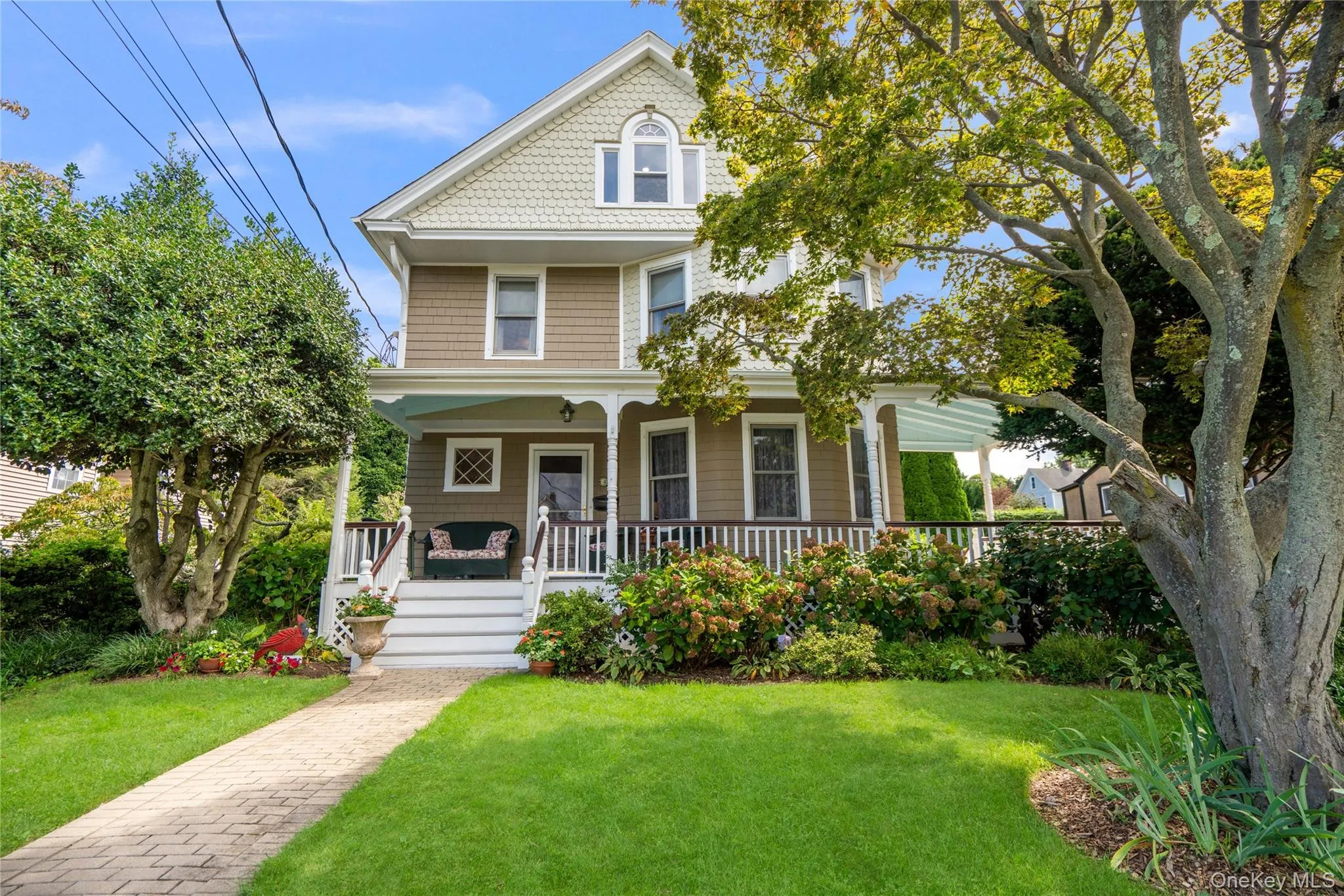 Multi-story residence featuring shingle siding, a covered front porch, and a dormer window Multi-story residence featuring shingle siding, a covered front porch, and a dormer window