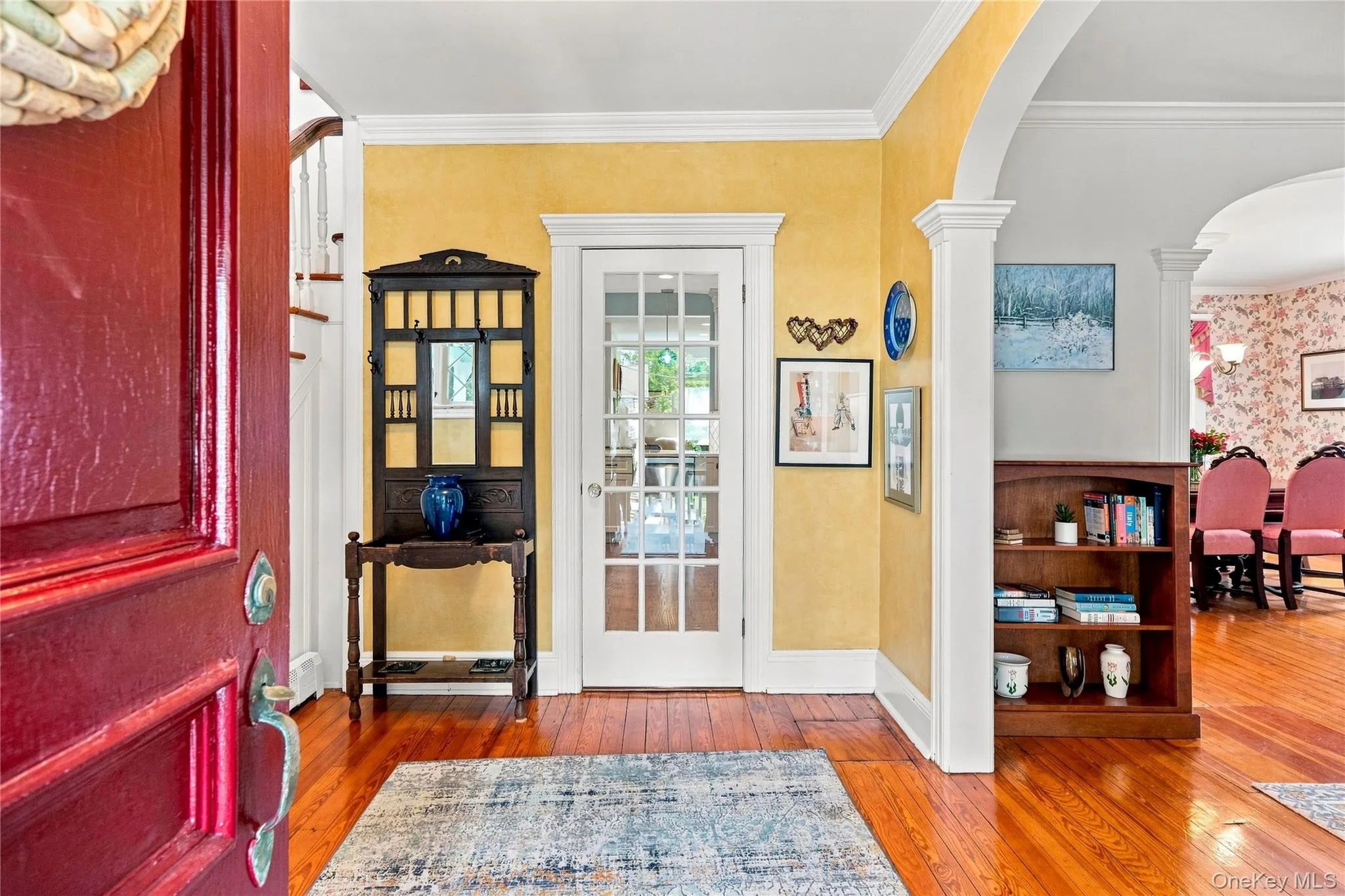 Hardwood flooring with a deep red entry door, a glass-paned interior door, and an arched doorway Hardwood flooring with a deep red entry door, a glass-paned interior door, and an arched doorway