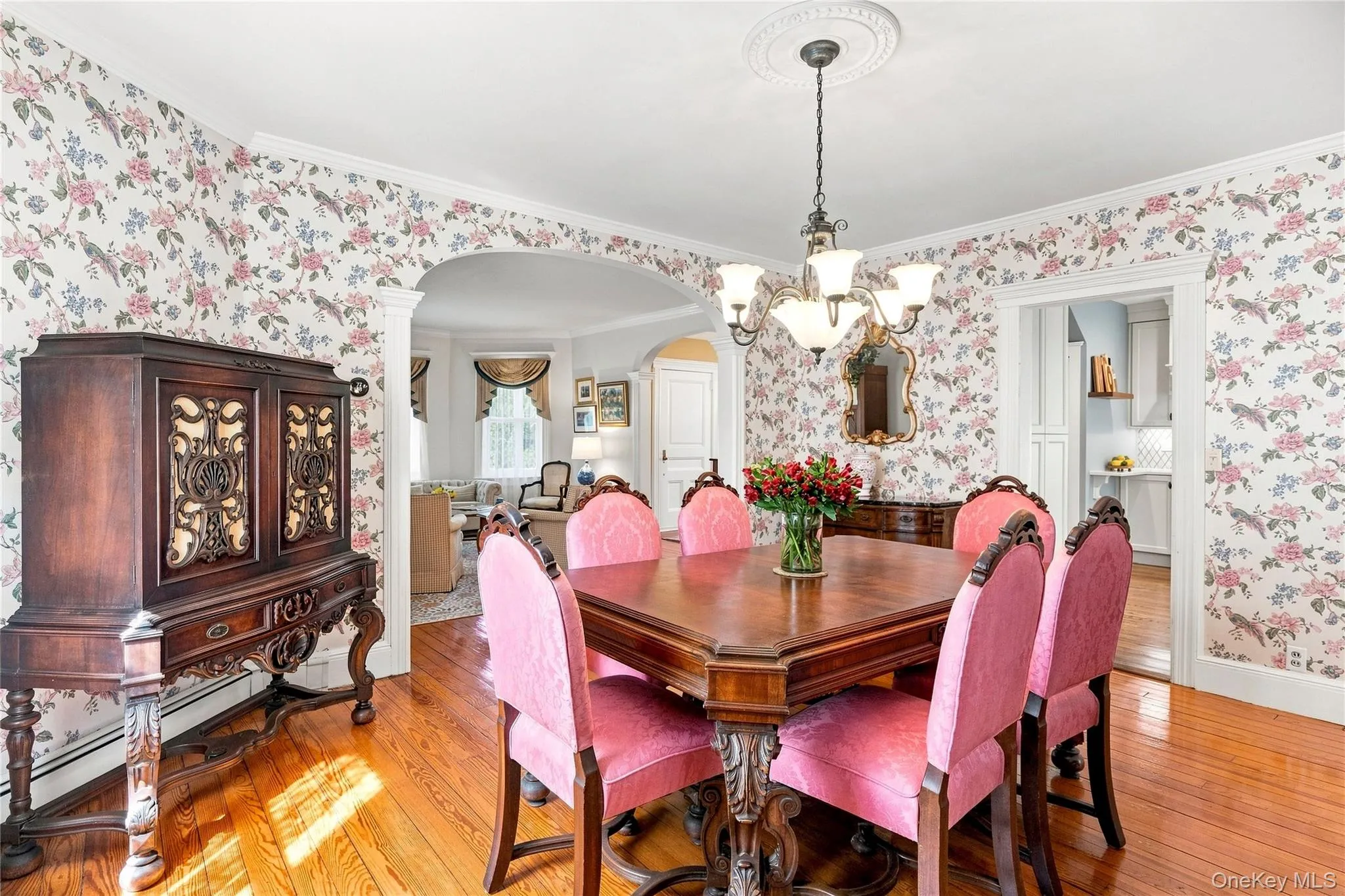 Hardwood flooring, decorative crown molding, and an arched doorway framing a sunlit room Hardwood flooring, decorative crown molding, and an arched doorway framing a sunlit room